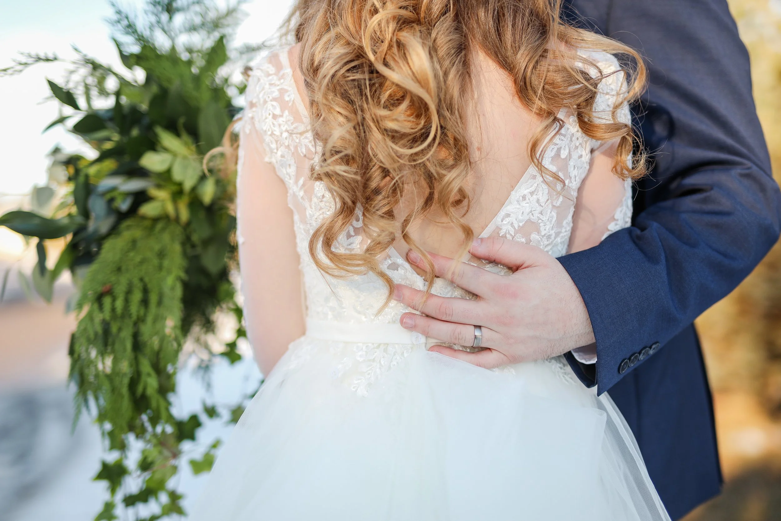 Close-up of a bride and groom embracing, with the groom's hand on the bride's chest, photographed by Minnesota based wedding photographer, LKW Photography.