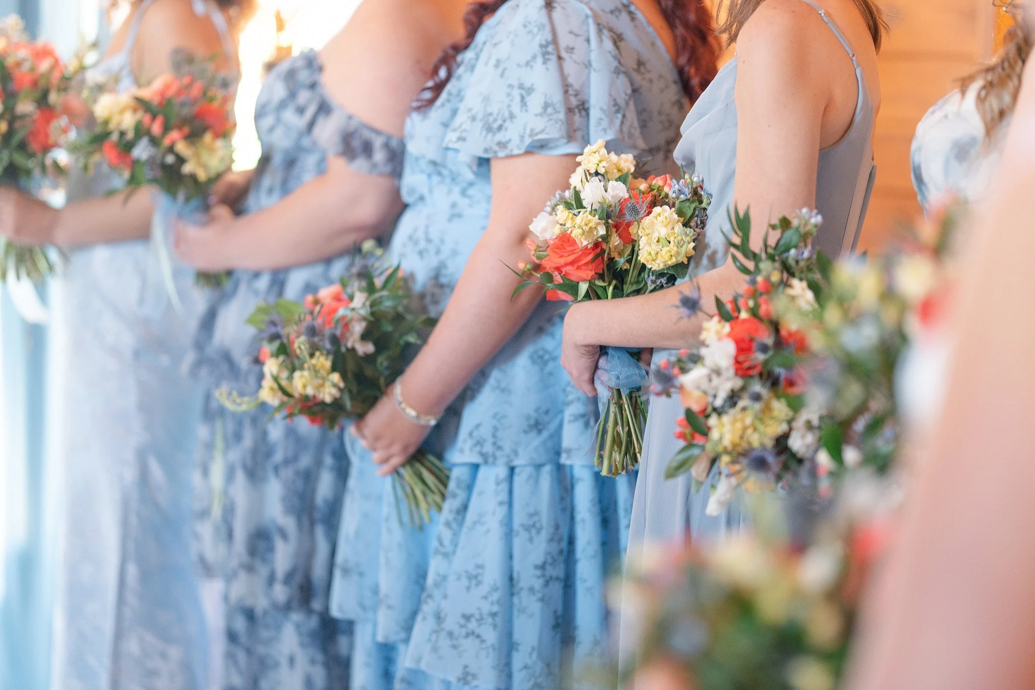 A line of women holding bouquets of flowers at a wedding.