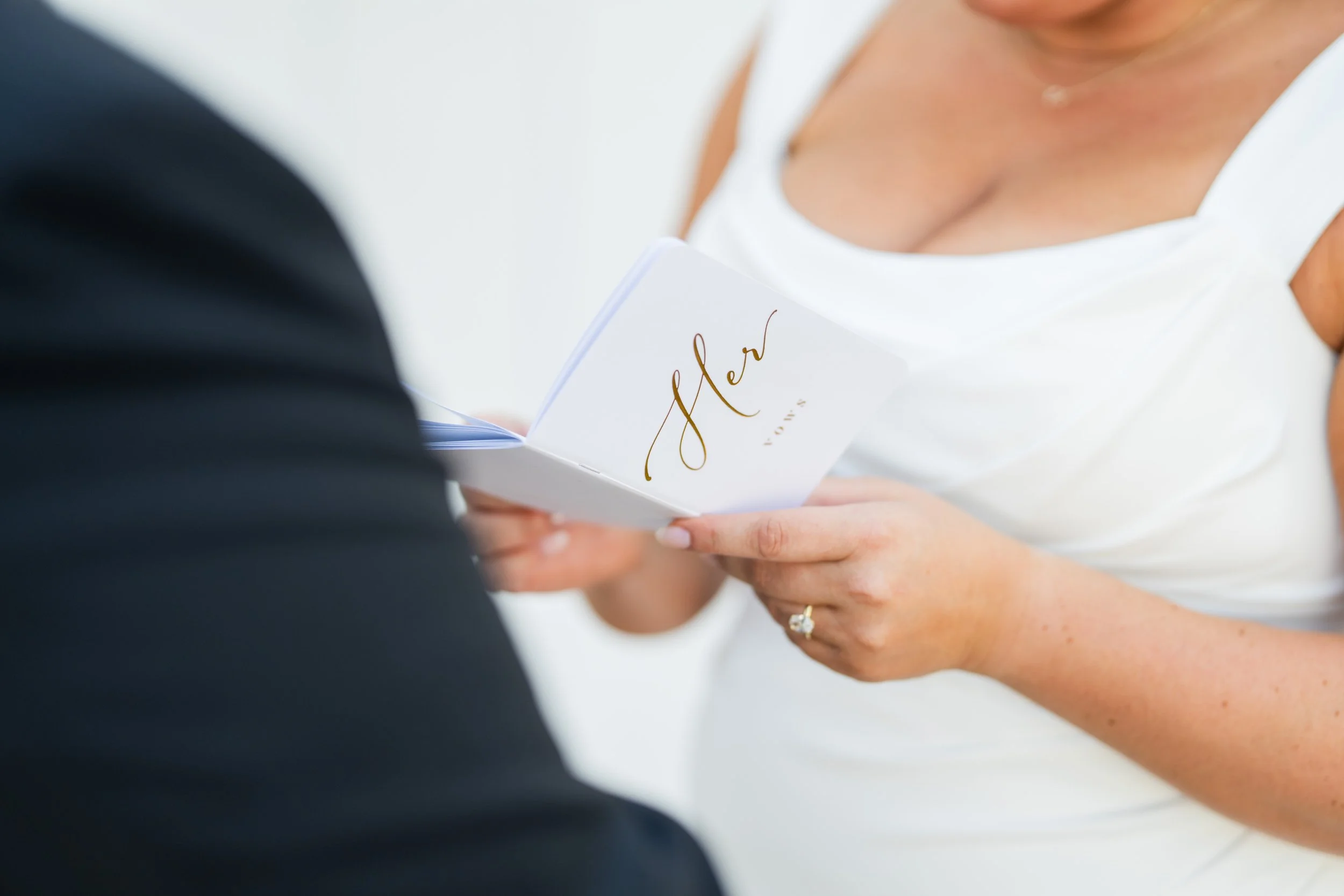 A bride reading her vows to her groom, with the emphasis being on her vows book, taken by MN photographer LKW Photography.
