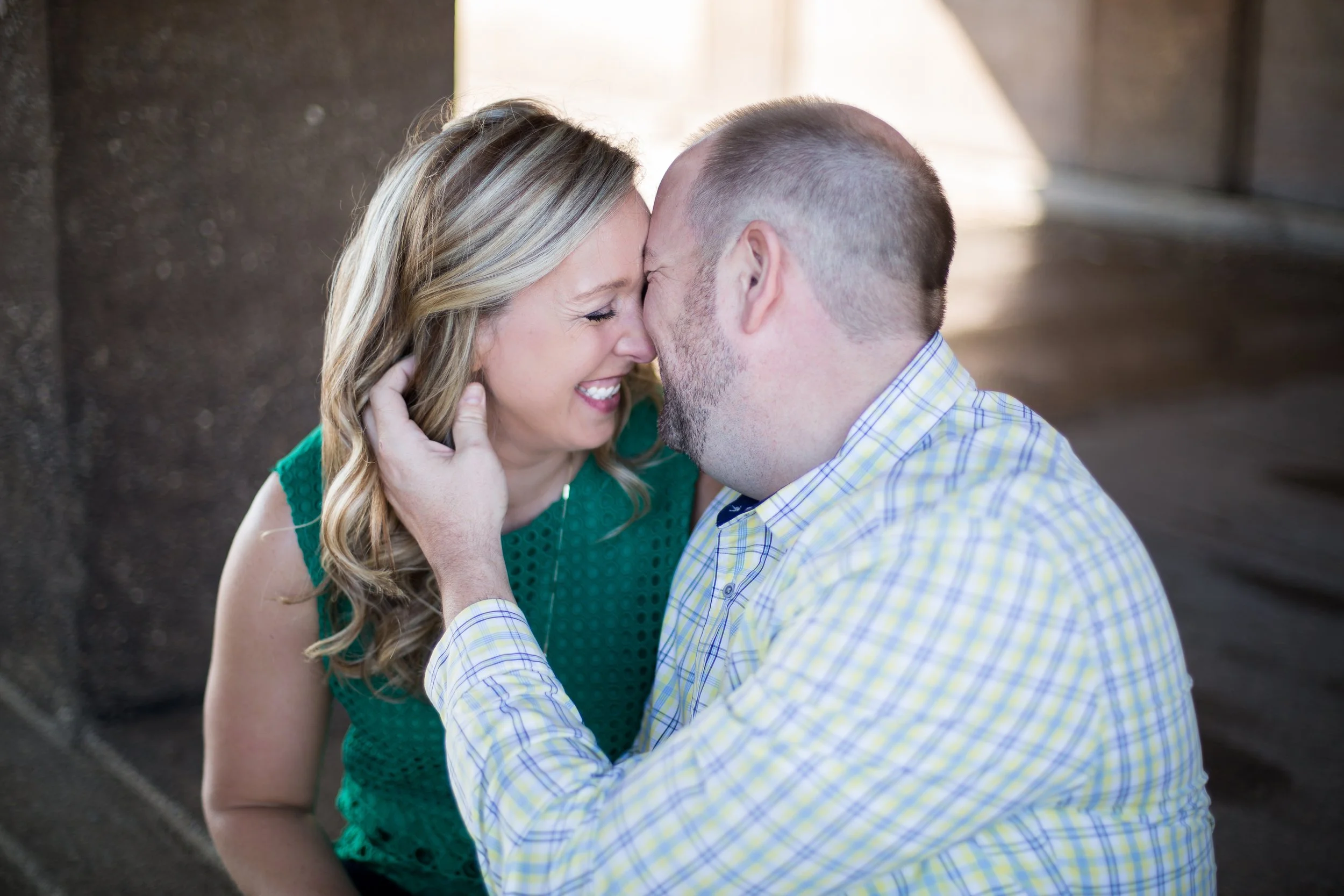 A couple touching foreheads and smiling, with minimal background lighting, taken by Minnesota based wedding photographer, LKW Photography.
