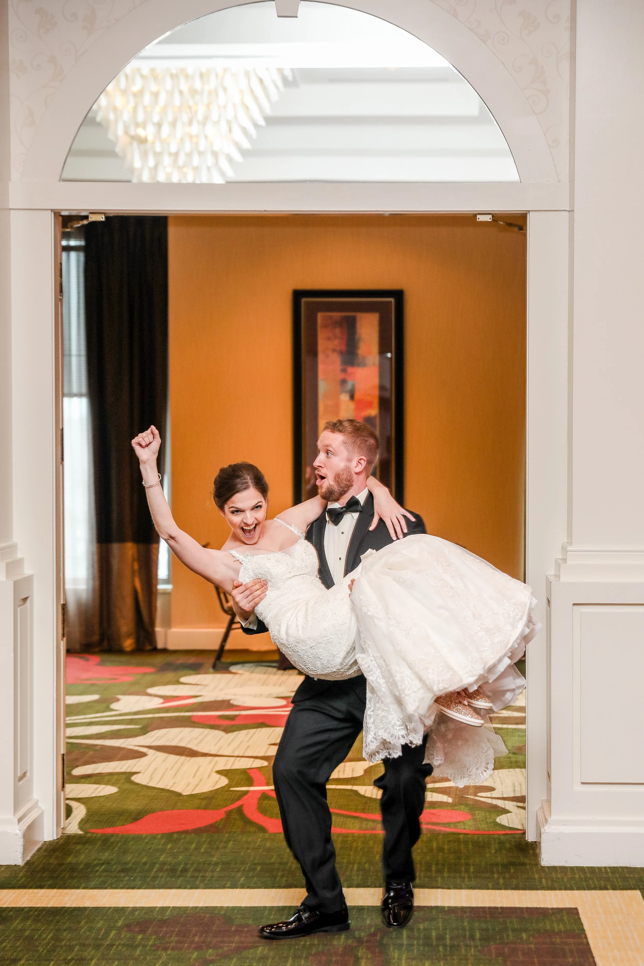A bride and groom dancing; the groom is carrying the bride and they are smiling and celebrating at their wedding reception, taken by Wedding Photographer, Leah Welch of LKW Photography.