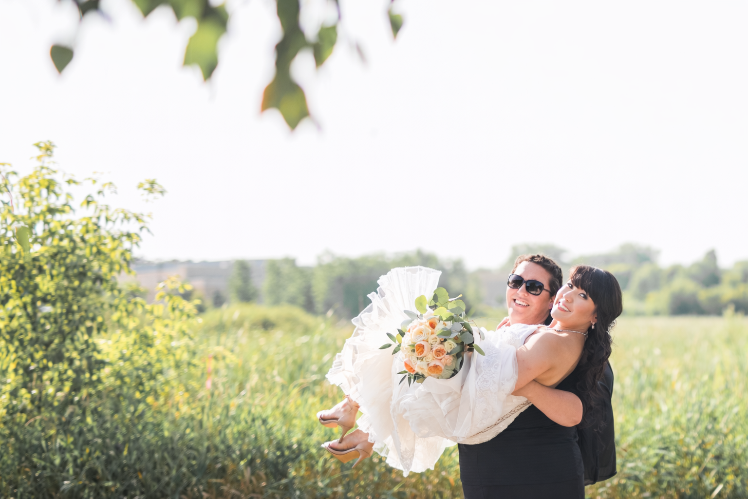 Minnesota based wedding photographer, Leah Welch of LKW Photography, carrying a bride so her dress doesn't get dirty.