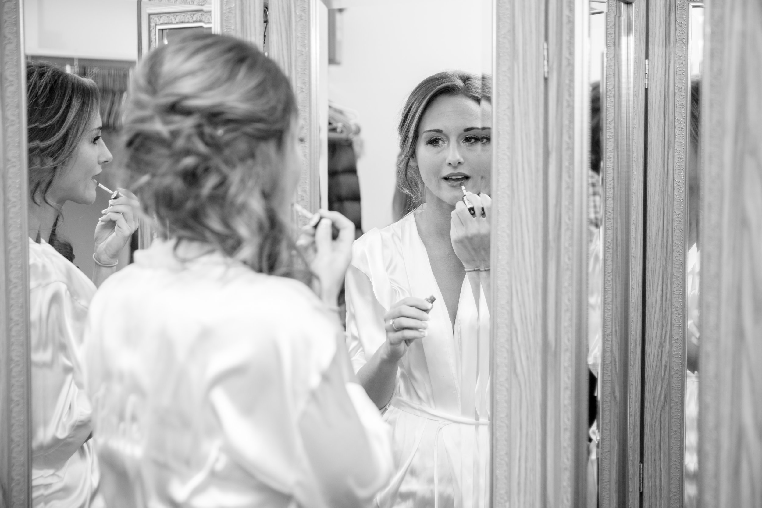 A bride applies lipstick in front of a mirror with multiple reflections, photographed by Minnesota based wedding photographer, LKW Photography.