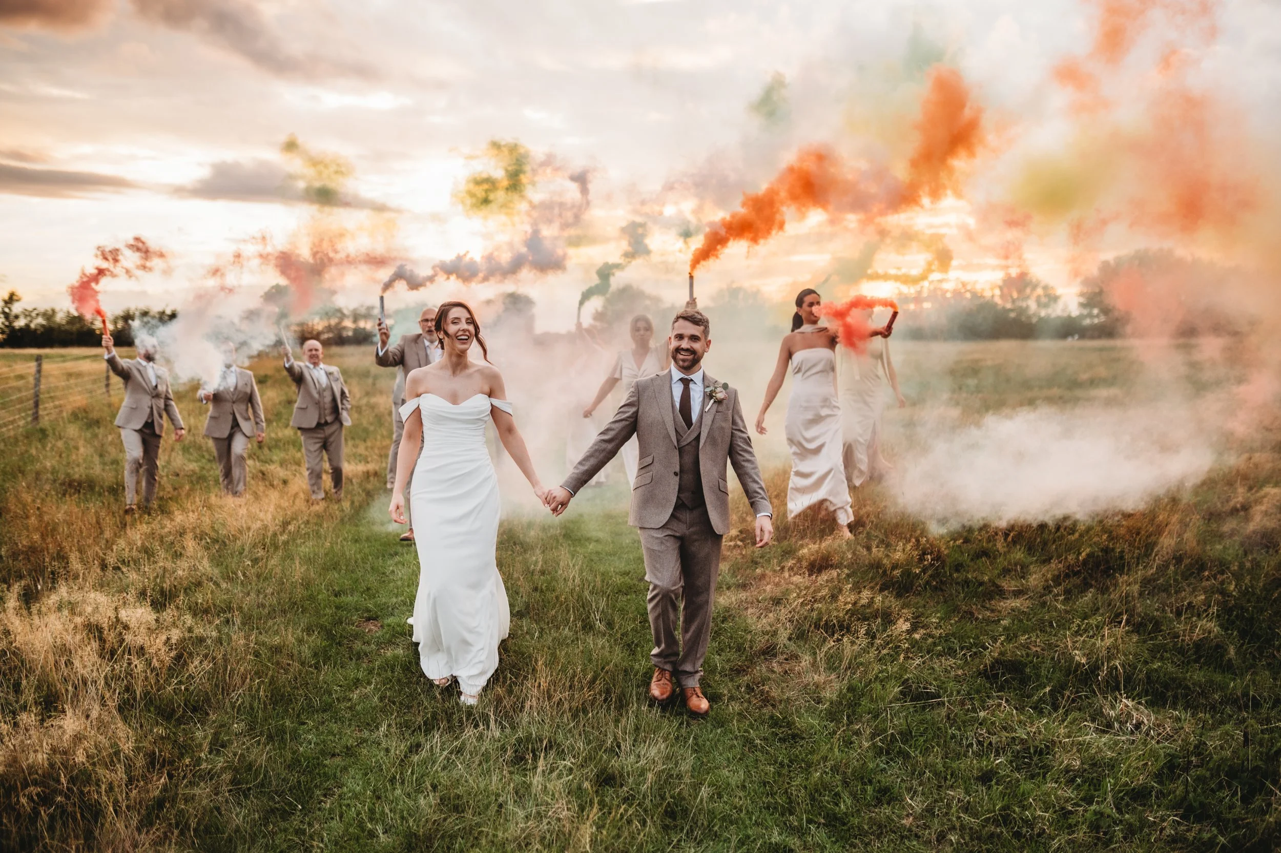 wedding couple waking through colourful smoke bombs at Godwick hall and great barn wedding venue in norfolk