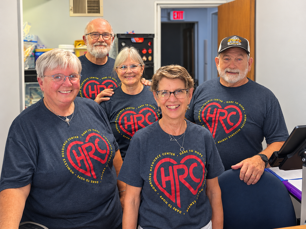 Five smiling HRC volunteers in matching navy Dare to Hope shirts at the HRC front desk