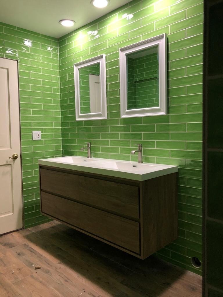 Green subway tile vanity wall with a floating double vanity by Arroyos Tile and Granite Inc.