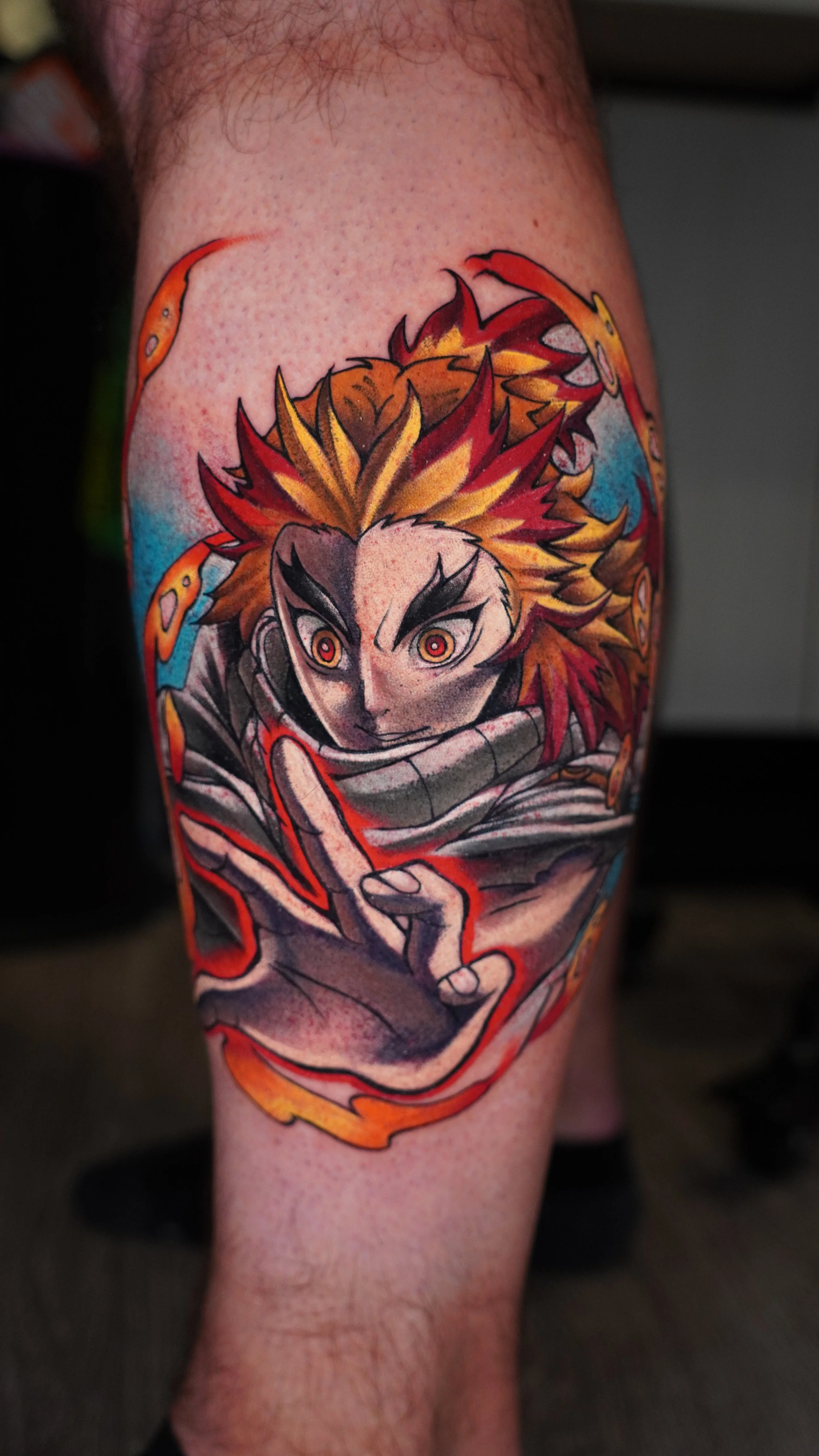 A colorful tattoo of a mashup consisting of Rengoku & Natsu with fiery hair, intense eyes, and a hand reaching forward, surrounded by vibrant flames and dynamic background.