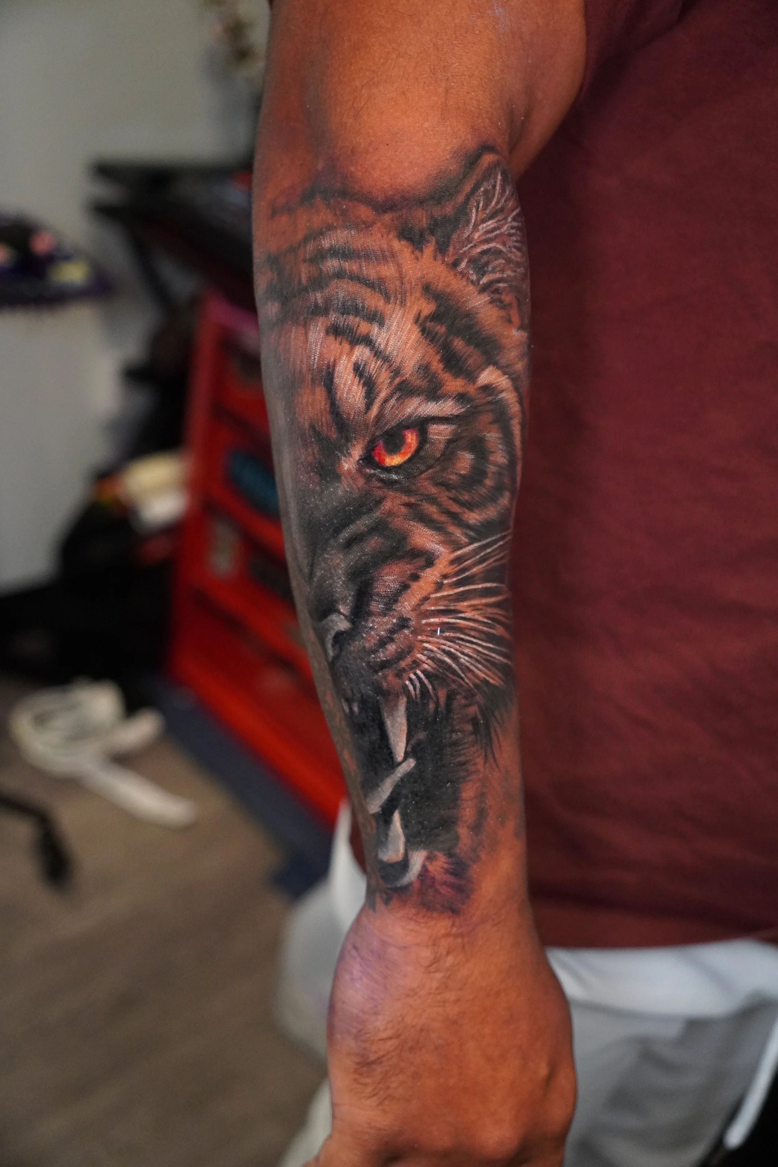 Cover up Tattoo of a roaring tiger's face on a person's forearm, with detailed fur and sharp teeth.