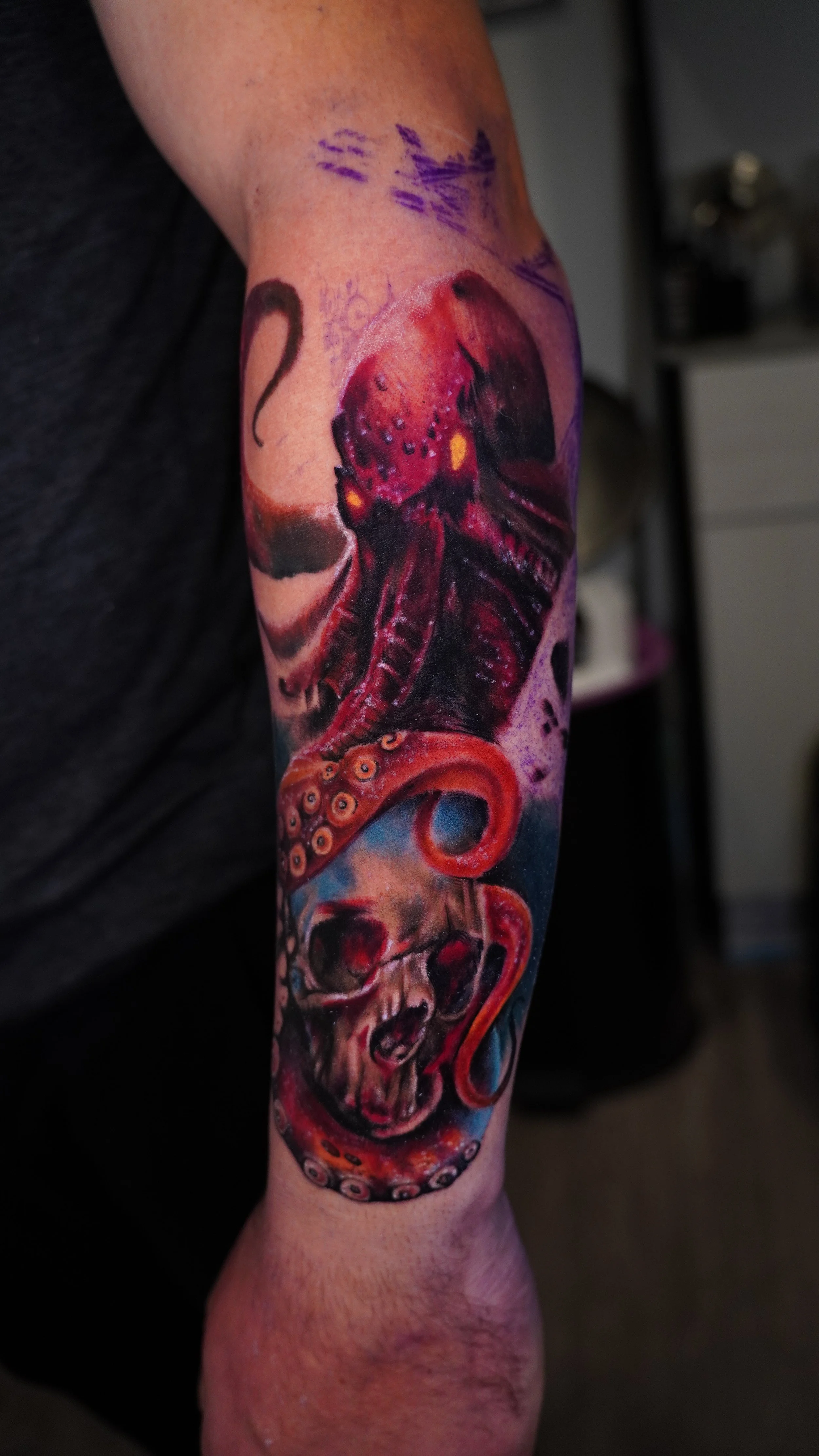 Tattoo of an octopus wrapping around a human skull on an arm.