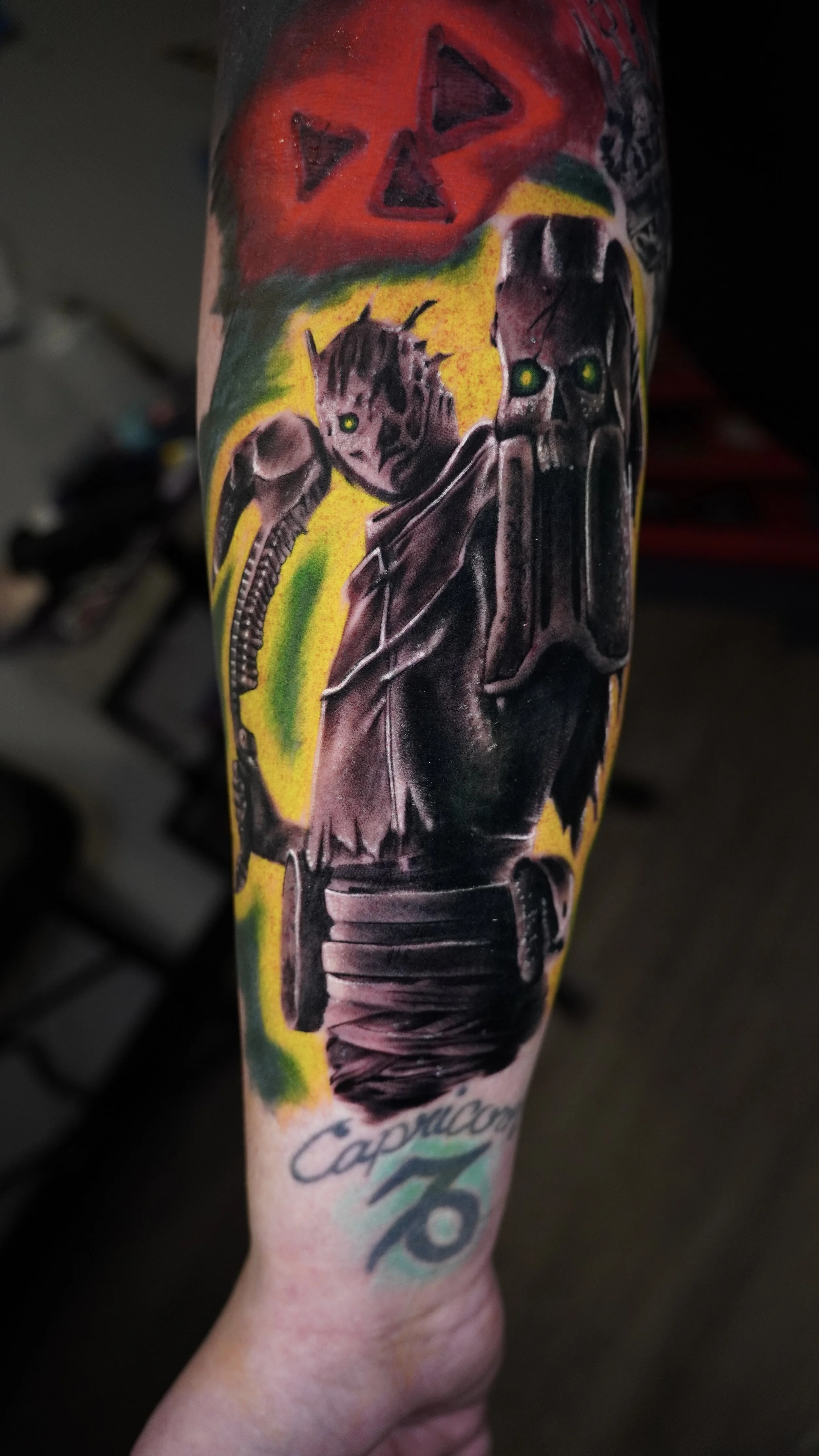 A tattoo on a person's arm featuring a Wraith from Dead By Daylight with a skeleton face, dressed in dark clothing with glowing green eyes, holding a skull/bell, with a colorful background.