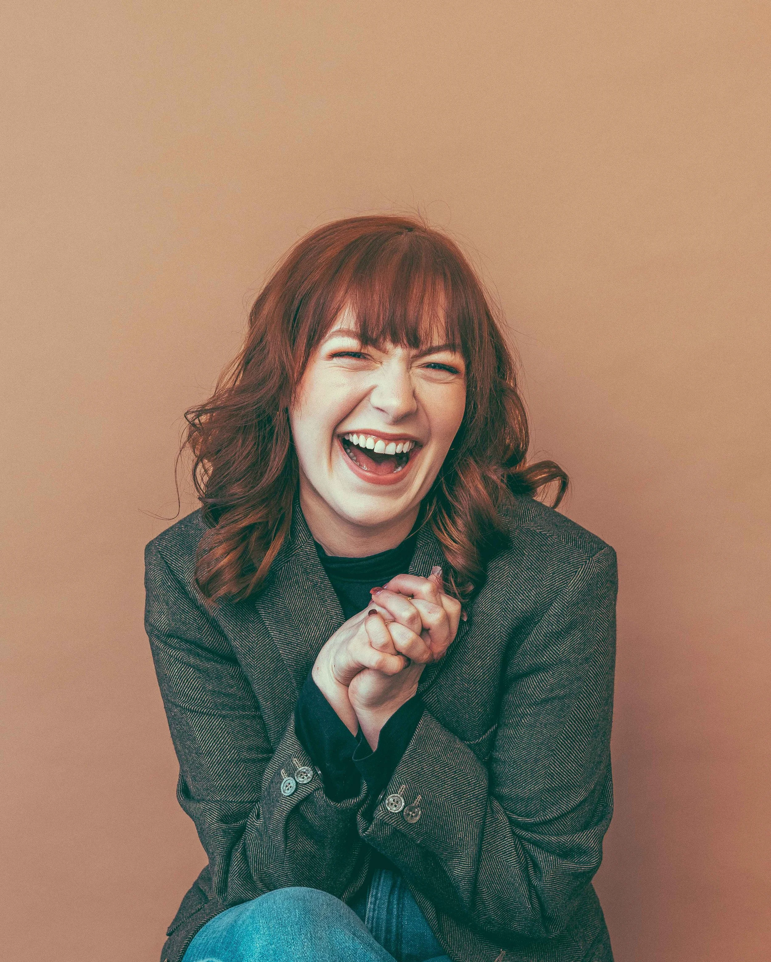 Ashlee, redheaded woman in a blazer, smiling, personal assistant to authors with Hawthorn & Aster