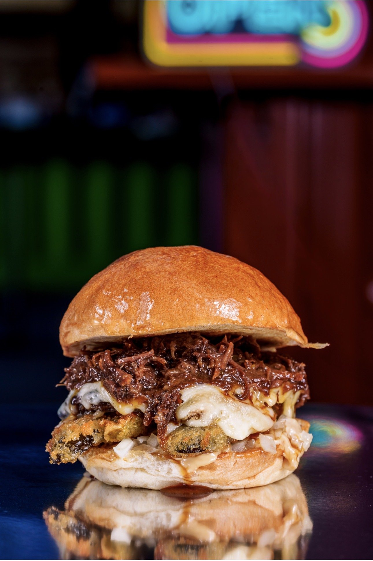 Close up of the cheeky stack burger with braised beef rib, cheese and fried pickles