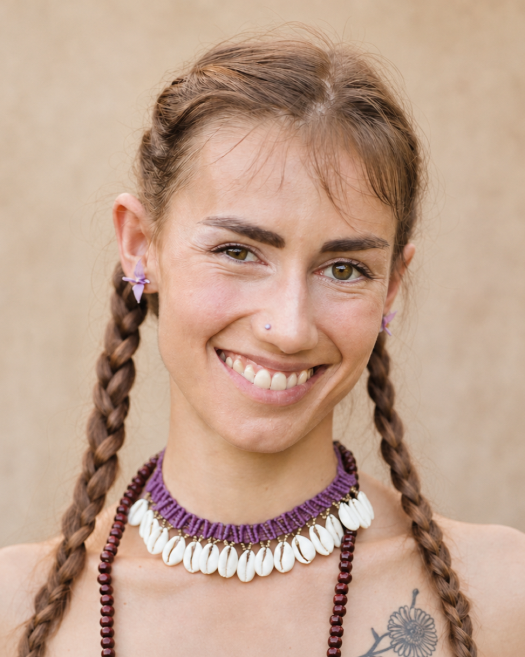 Portrait of Nina smiling outdoors, wearing braided hair and a shell necklace.