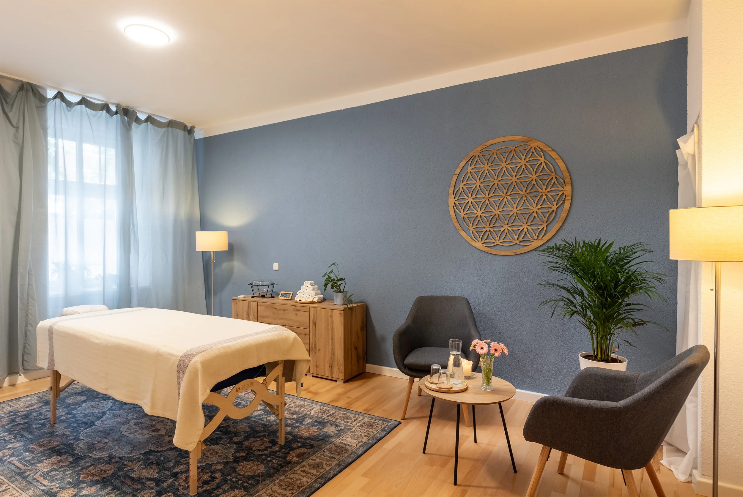 A spacious blue treatment room at Harmonie Studio with a massage table and consultation area
