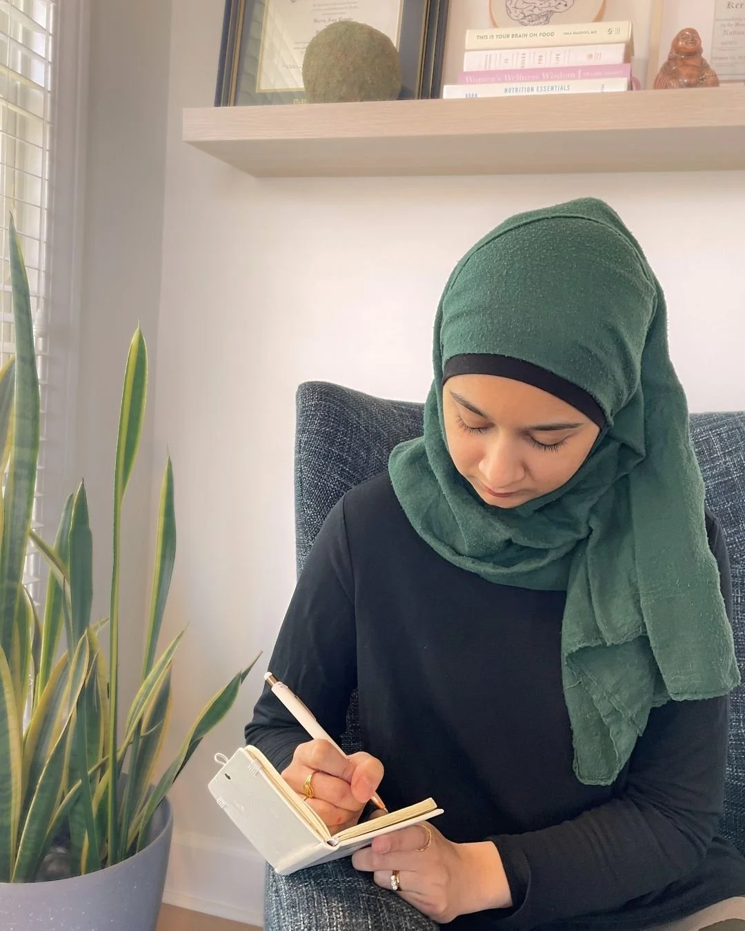 A woman wearing a hijab writes in a journal