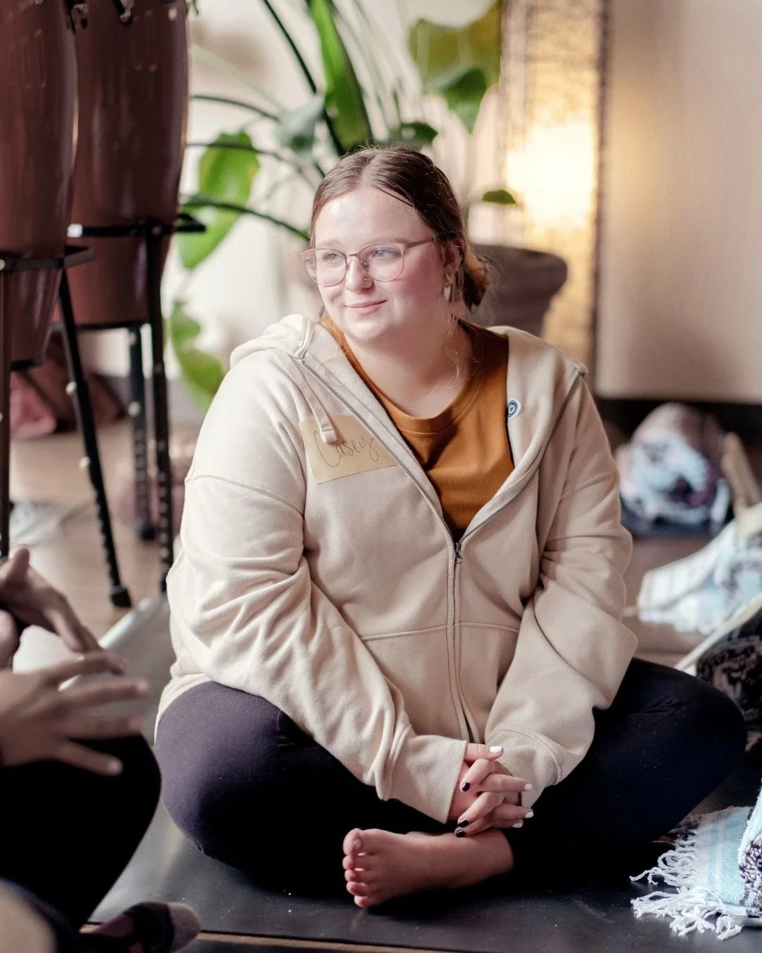Reset therapist Casey Young sits cross legged on a yoga mat.