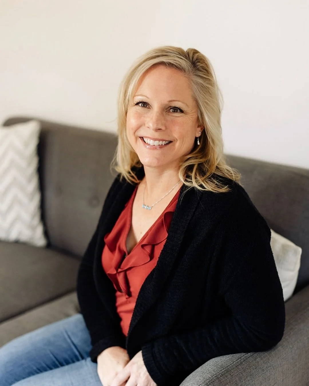 Reset therapist Lisa McIntyre smiles from a cozy couch.