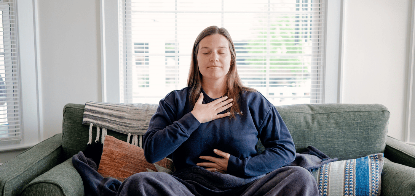 A woman practices mindfulness on a green couch