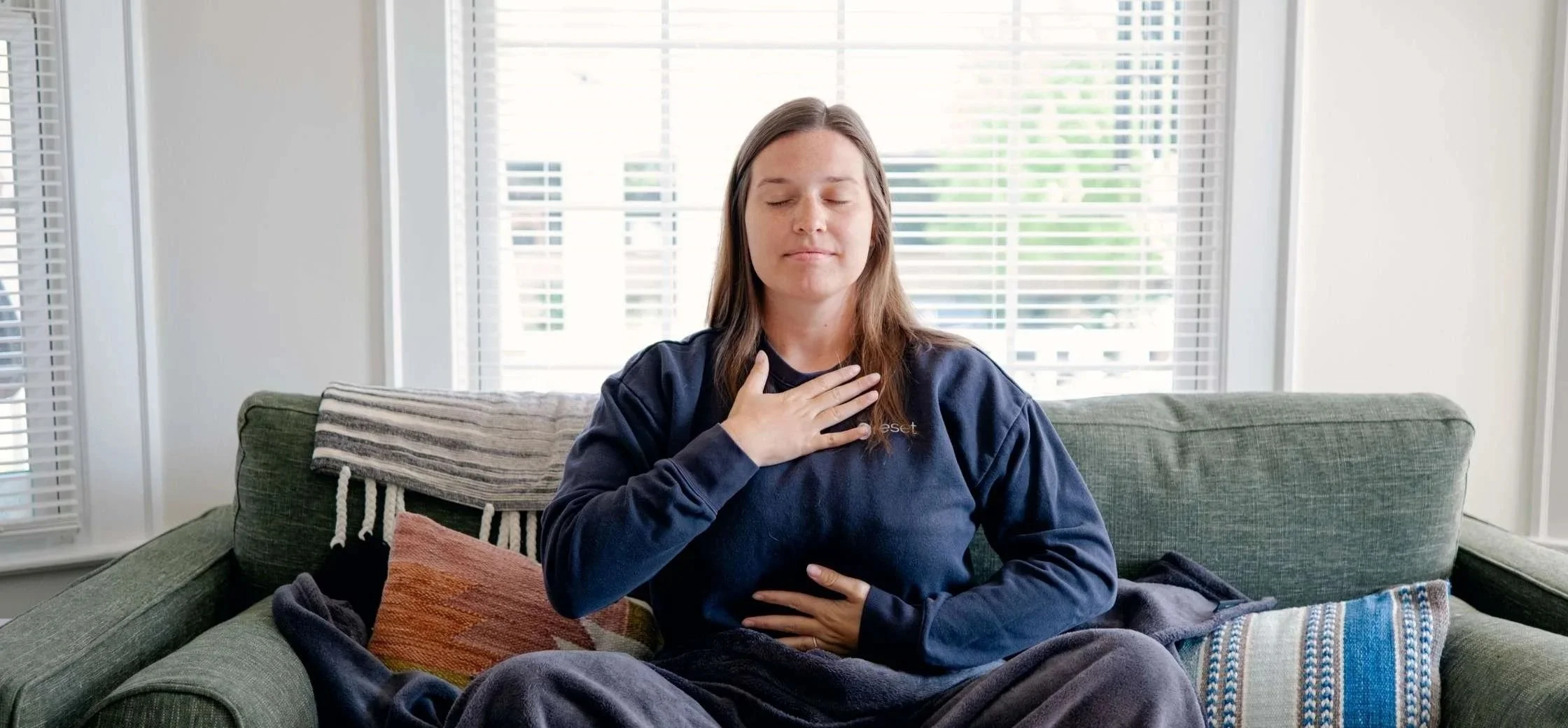 A woman practices mindfulness on a green couch