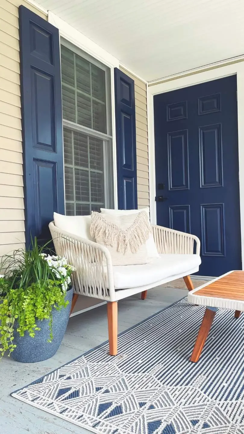 There is a couch next to a planter in front of a window on the porch of the Reset Plymouth office