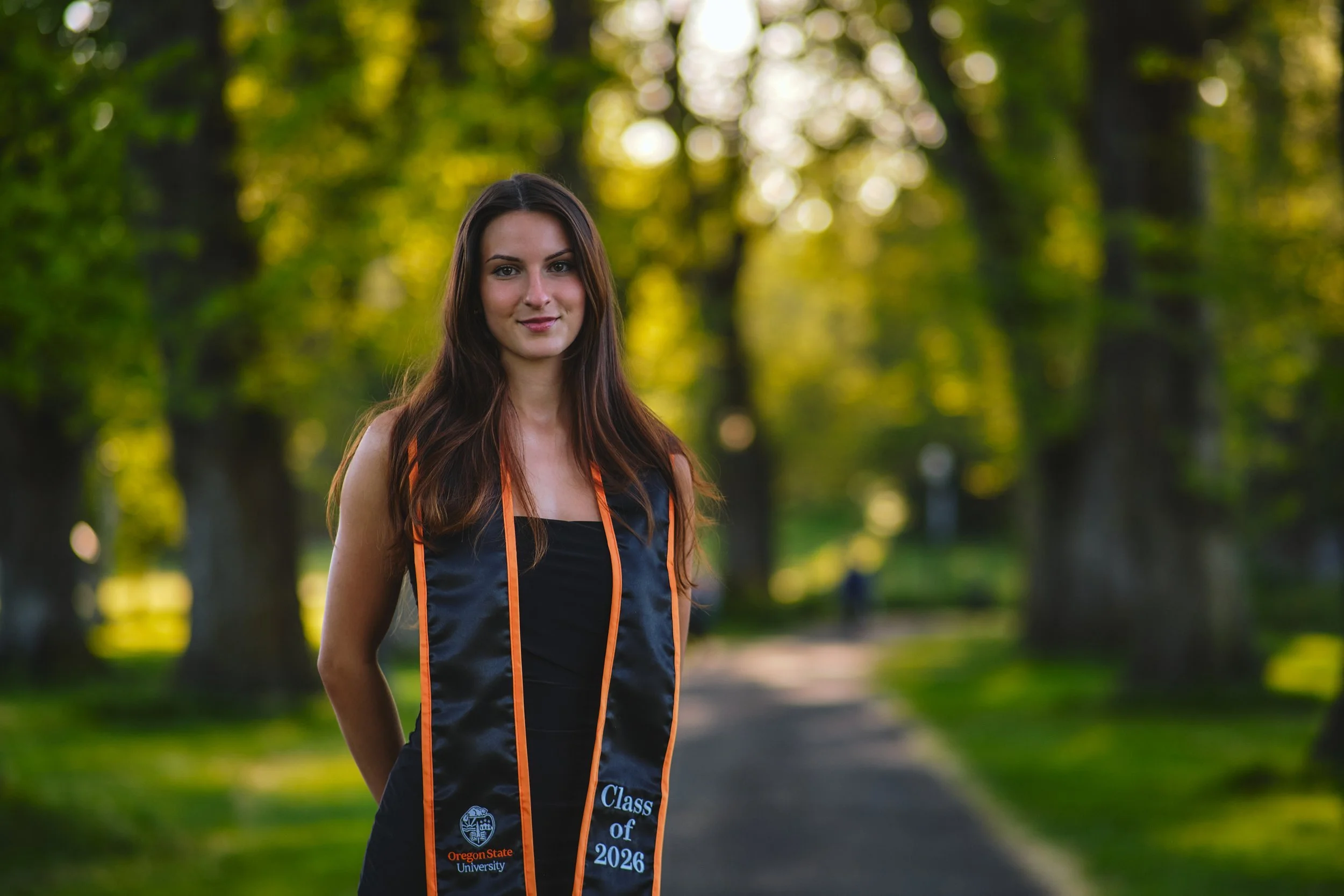 Oregon State graduate on a tree-lined campus path in Corvallis