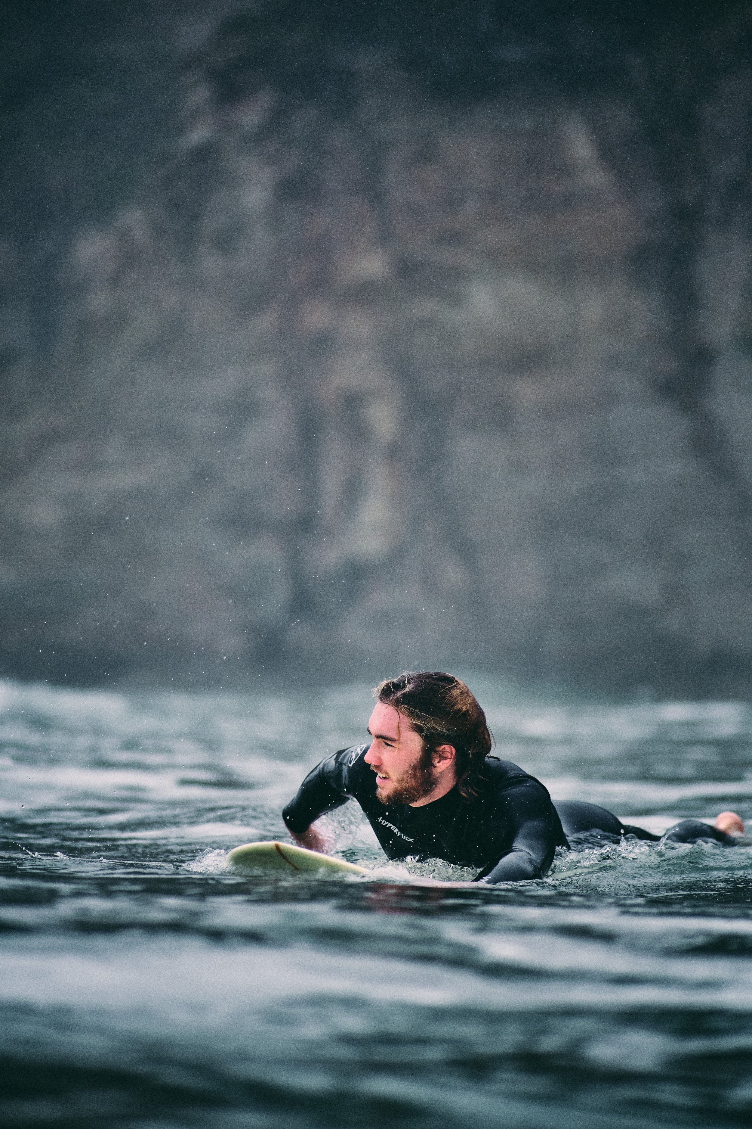 Surfer paddling out in cold Pacific water