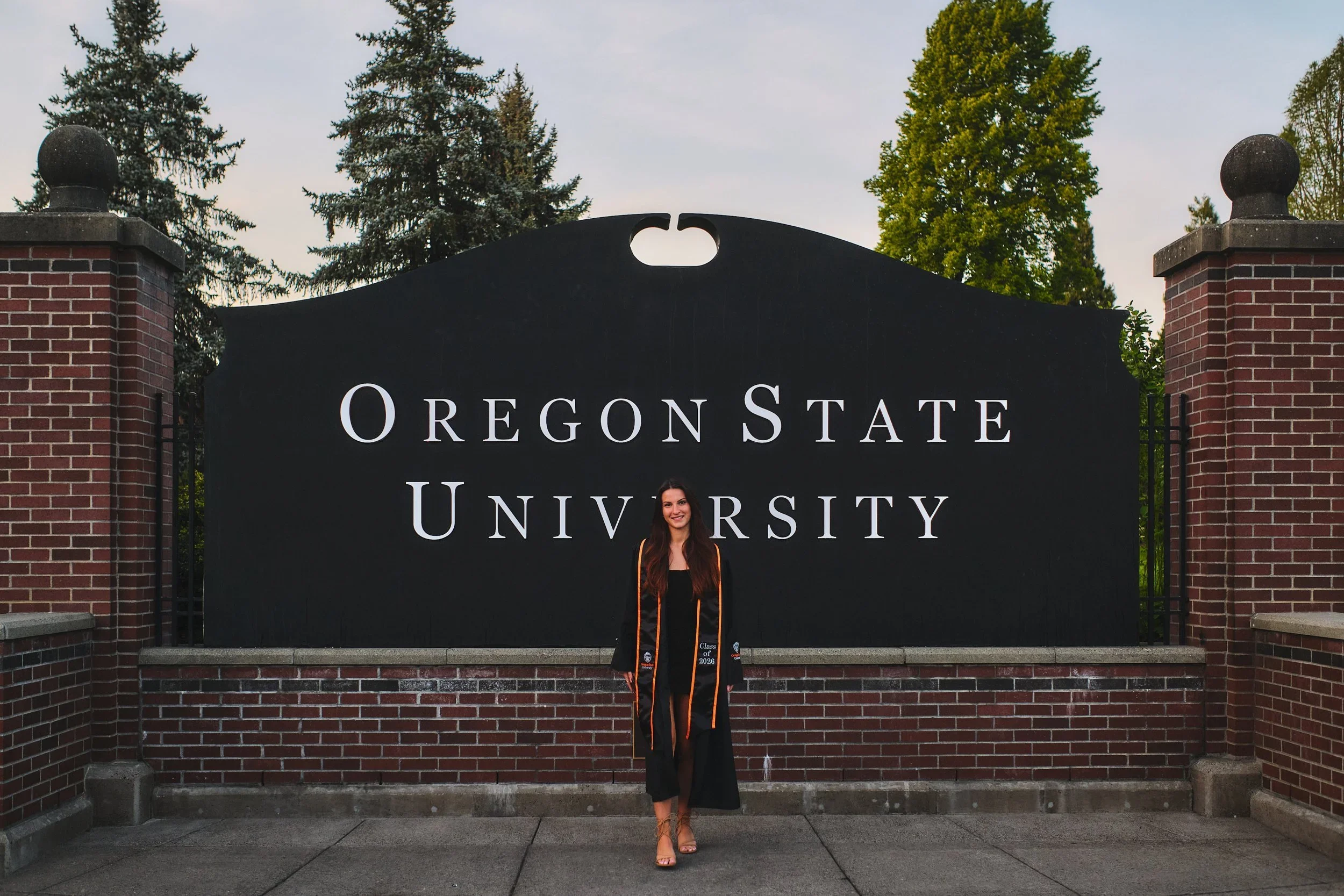 Graduate at the Oregon State University entrance sign in Corvallis, Oregon