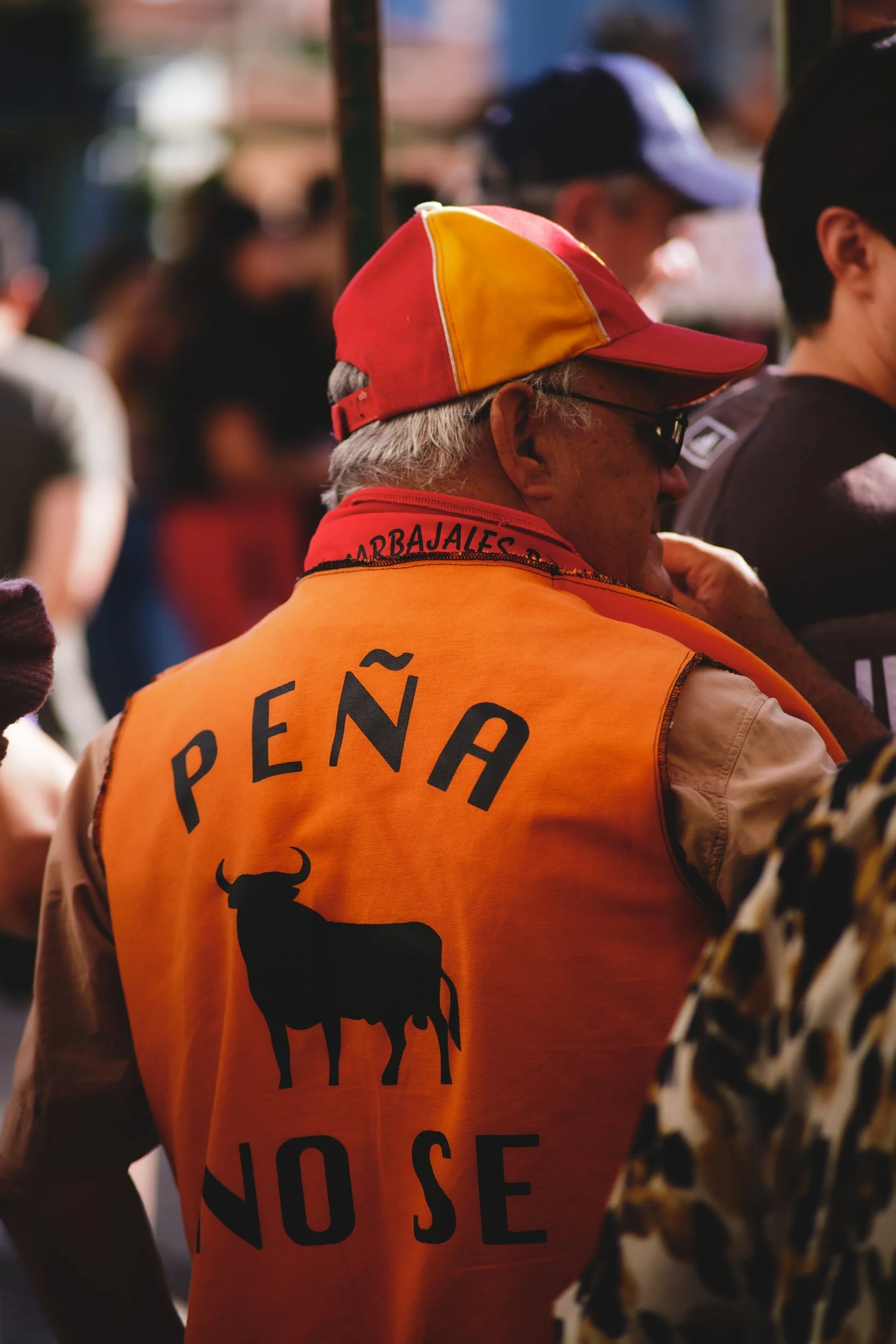 Man in an orange peña vest at a village fiesta in Spain