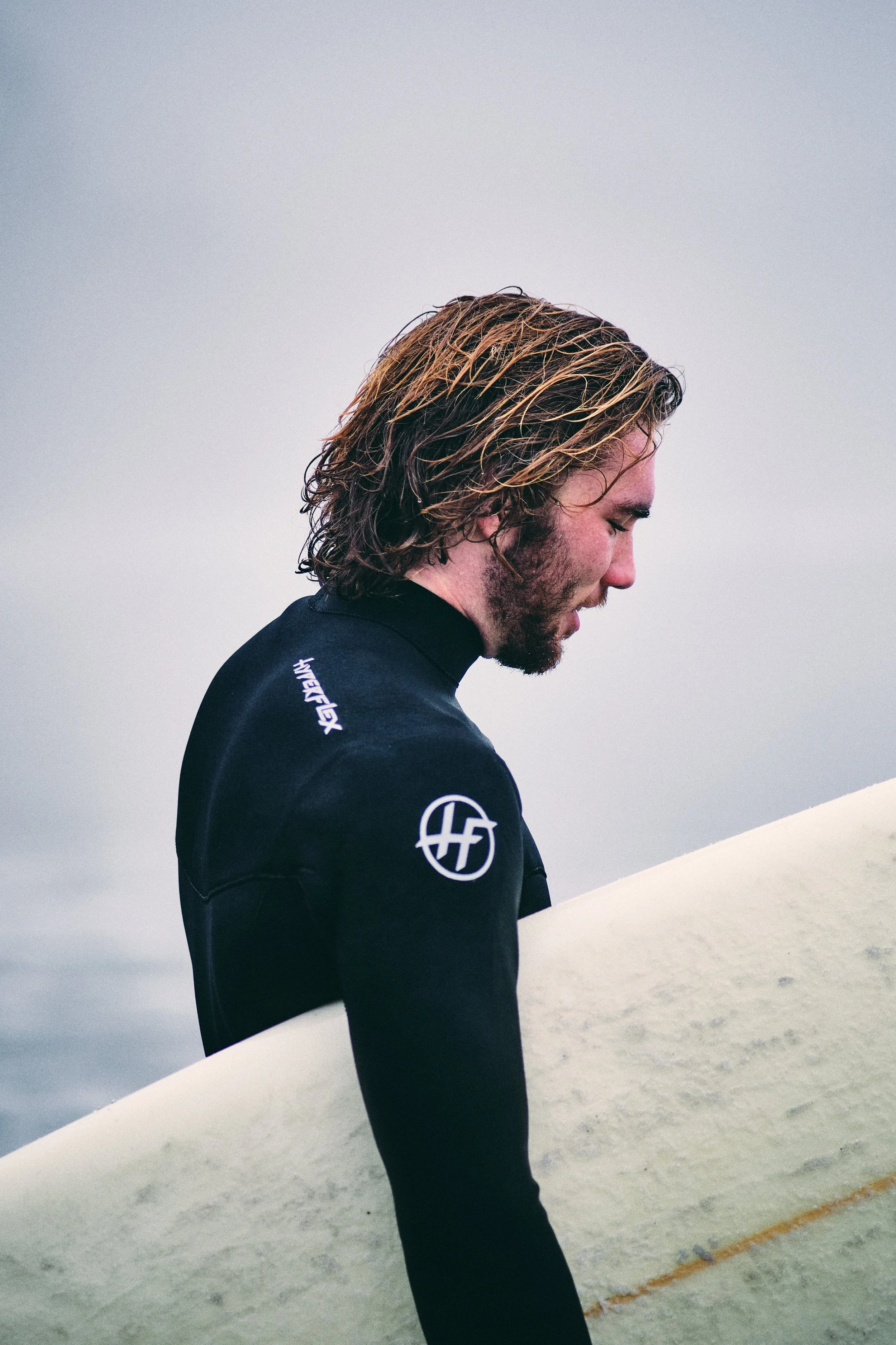 Surfer in a wetsuit holding a surfboard