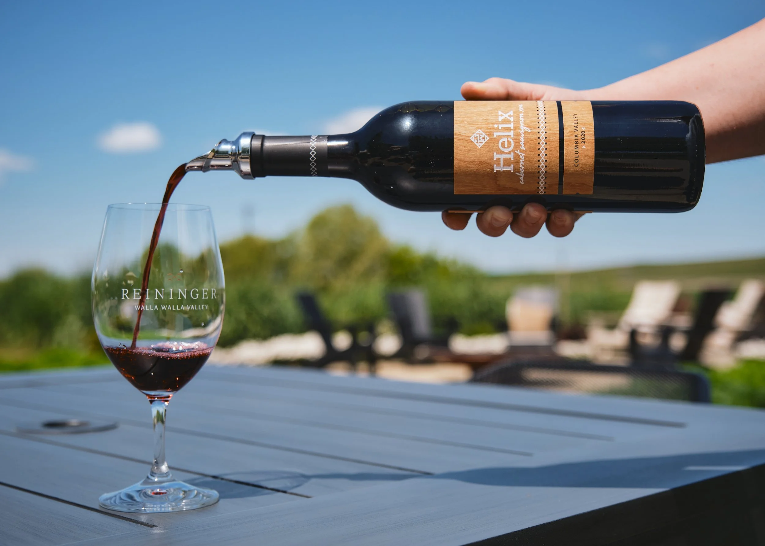 Red wine being poured into a glass on a sunny winery patio