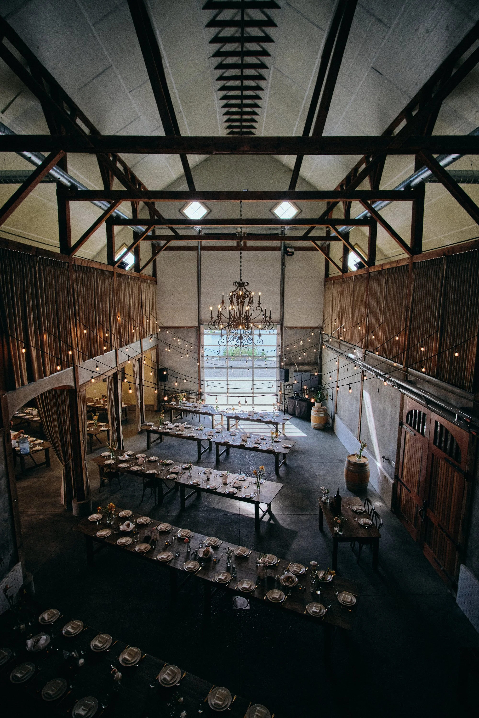 Barn wedding and event venue with long tables and a chandelier, venue photography