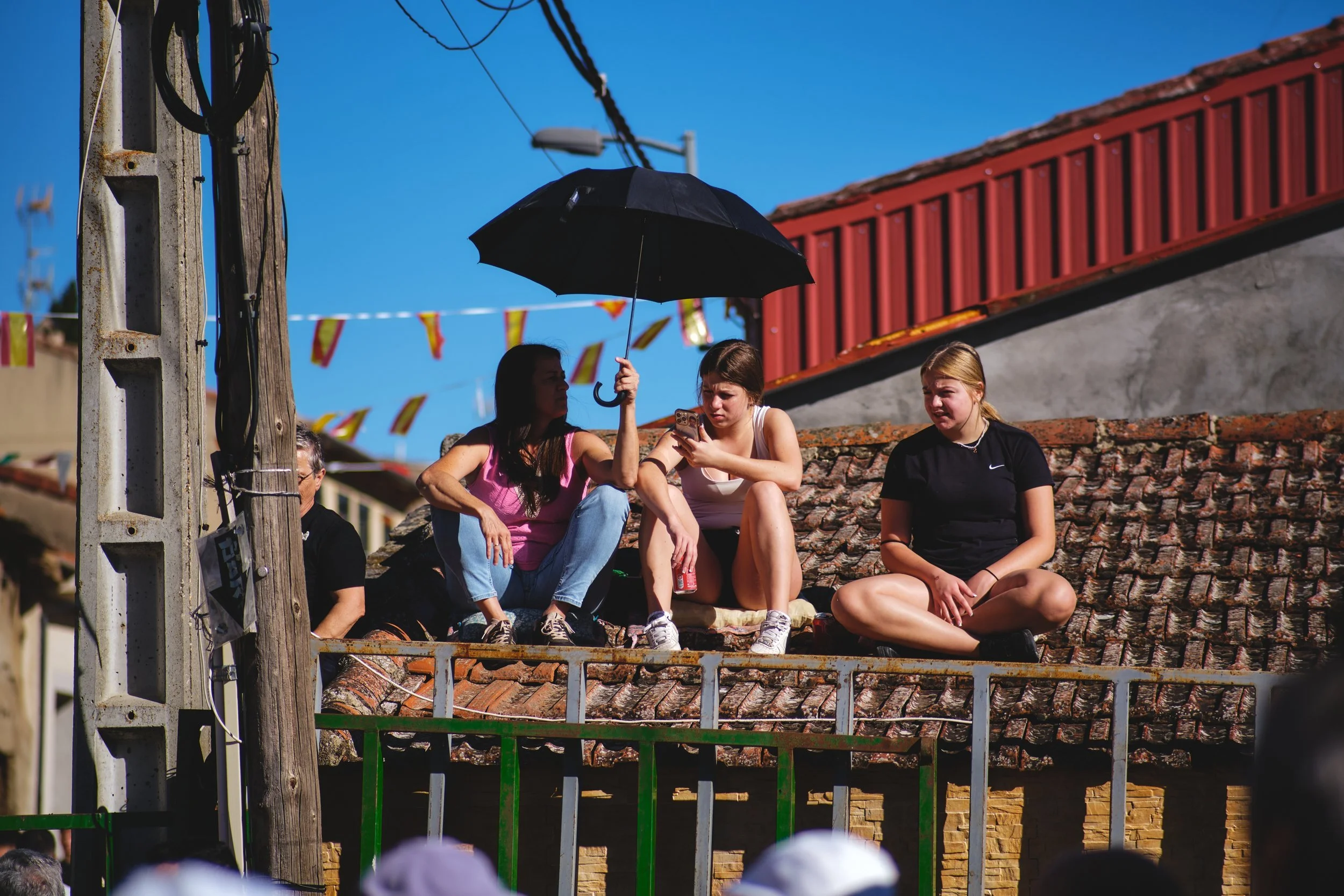 Fiesta-goers on a rooftop under an umbrella in Spain