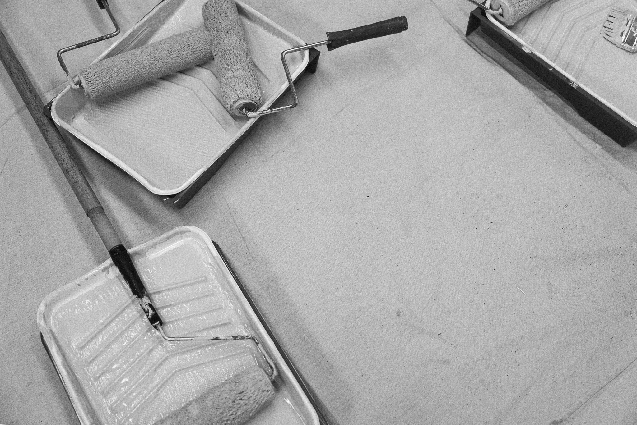 Paint rollers and trays used for painting on the floor.