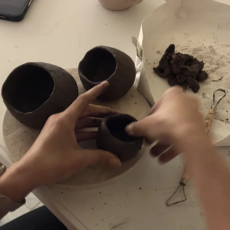 hands thinning out a clay wall
