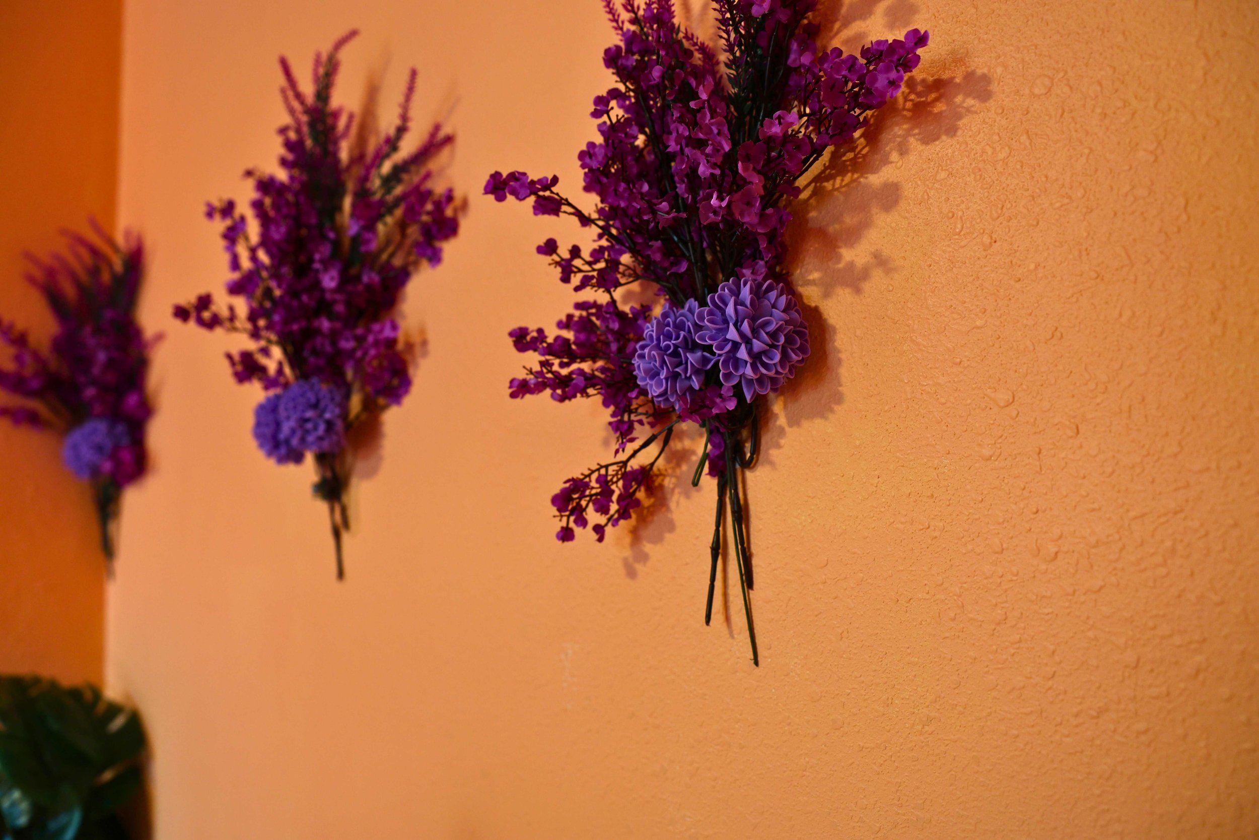 Purple floral wall decor on orange textured wall
