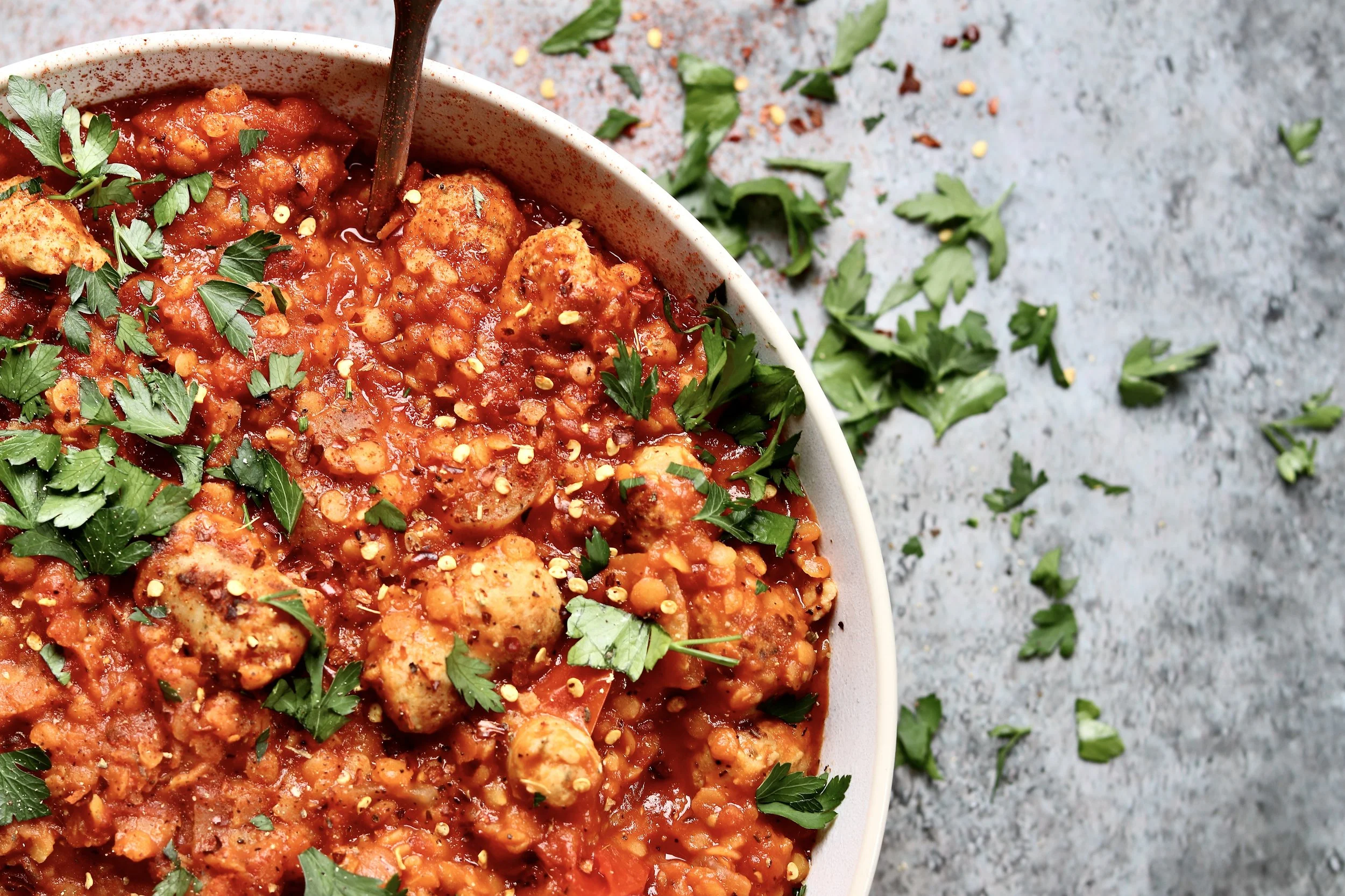 High-protein sausage and red lentil power pot recipe in tomato sauce topped with parsley.