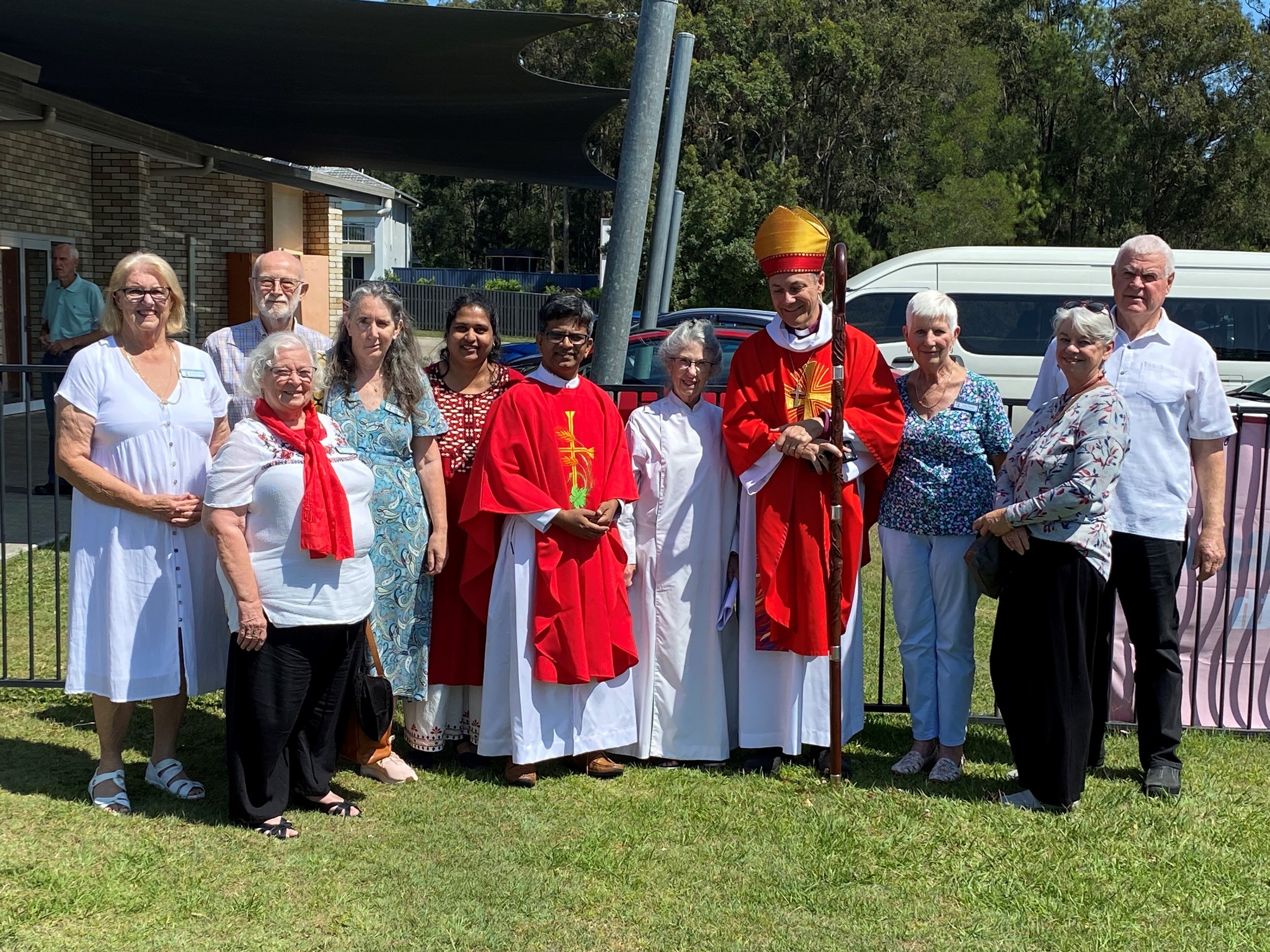 Group of people standing outdoors, some in religious robes, celebrating a religious event.