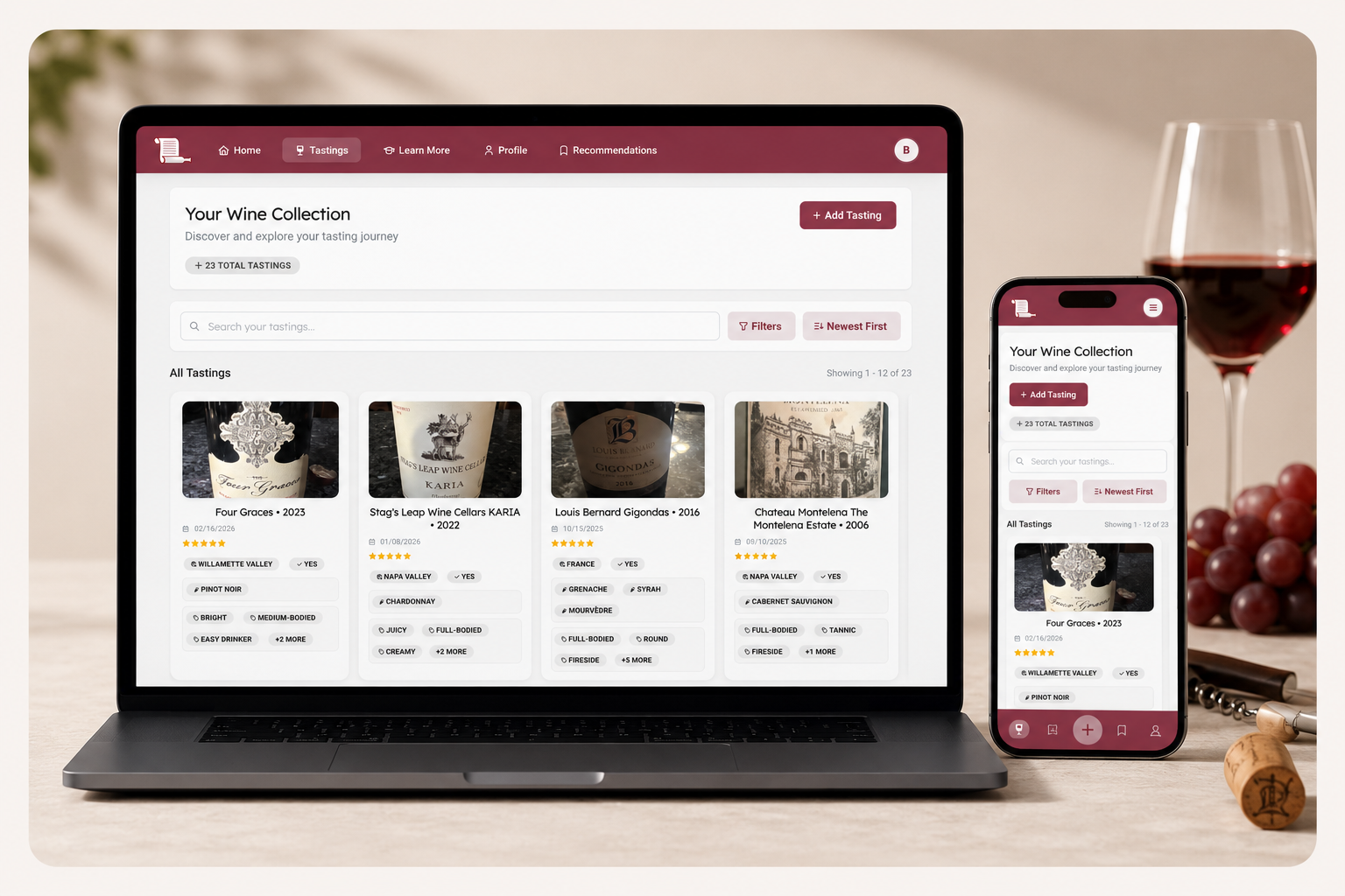 Laptop and smartphone displaying the Somm Scribe wine journal tasting collection, surrounded by a glass of red wine, grapes, cork and corkscrew.