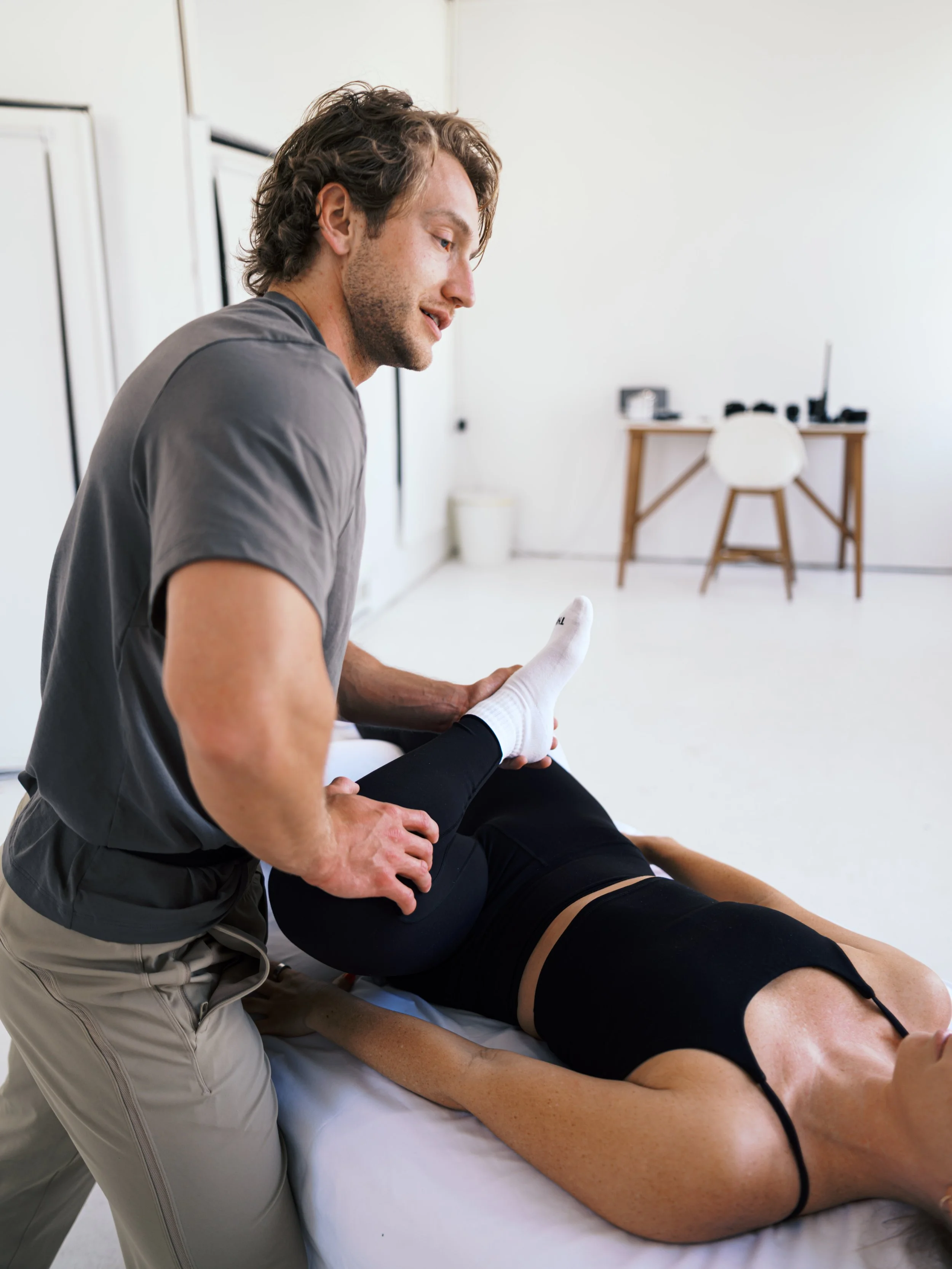 A woman performing stretch therapy and massage techniques on a client.