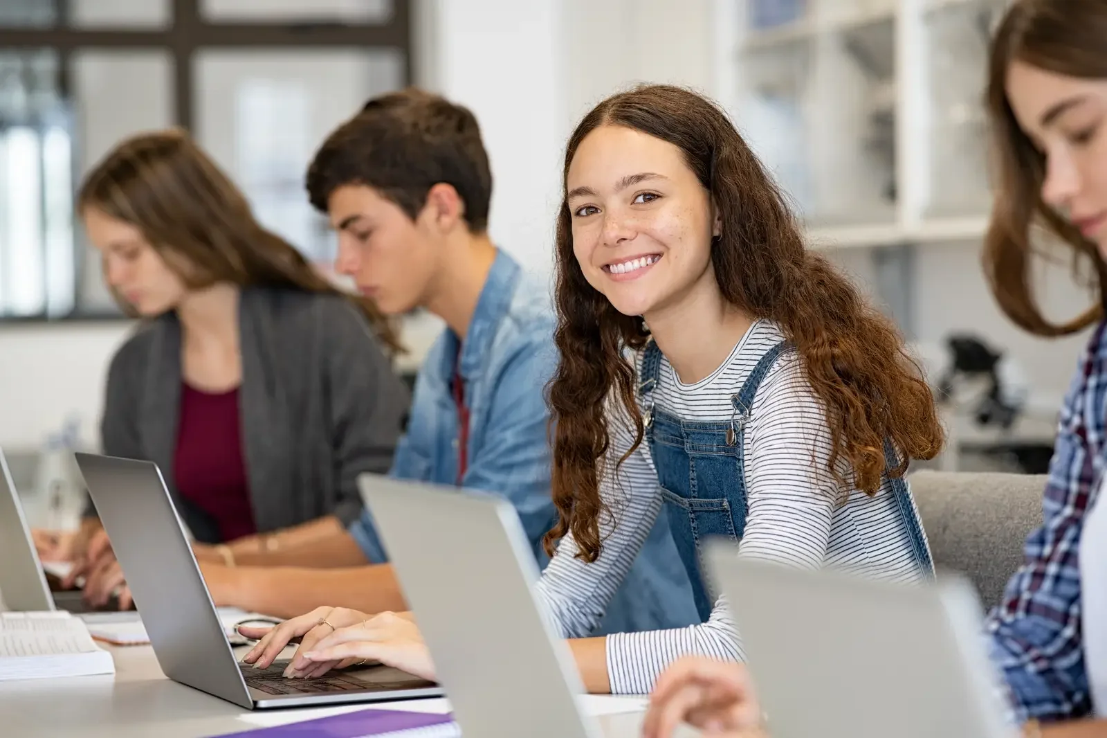 Teen students writing code on laptops in a bright modern classroom — Aprise Learning Python Foundations course for Grades 7–10