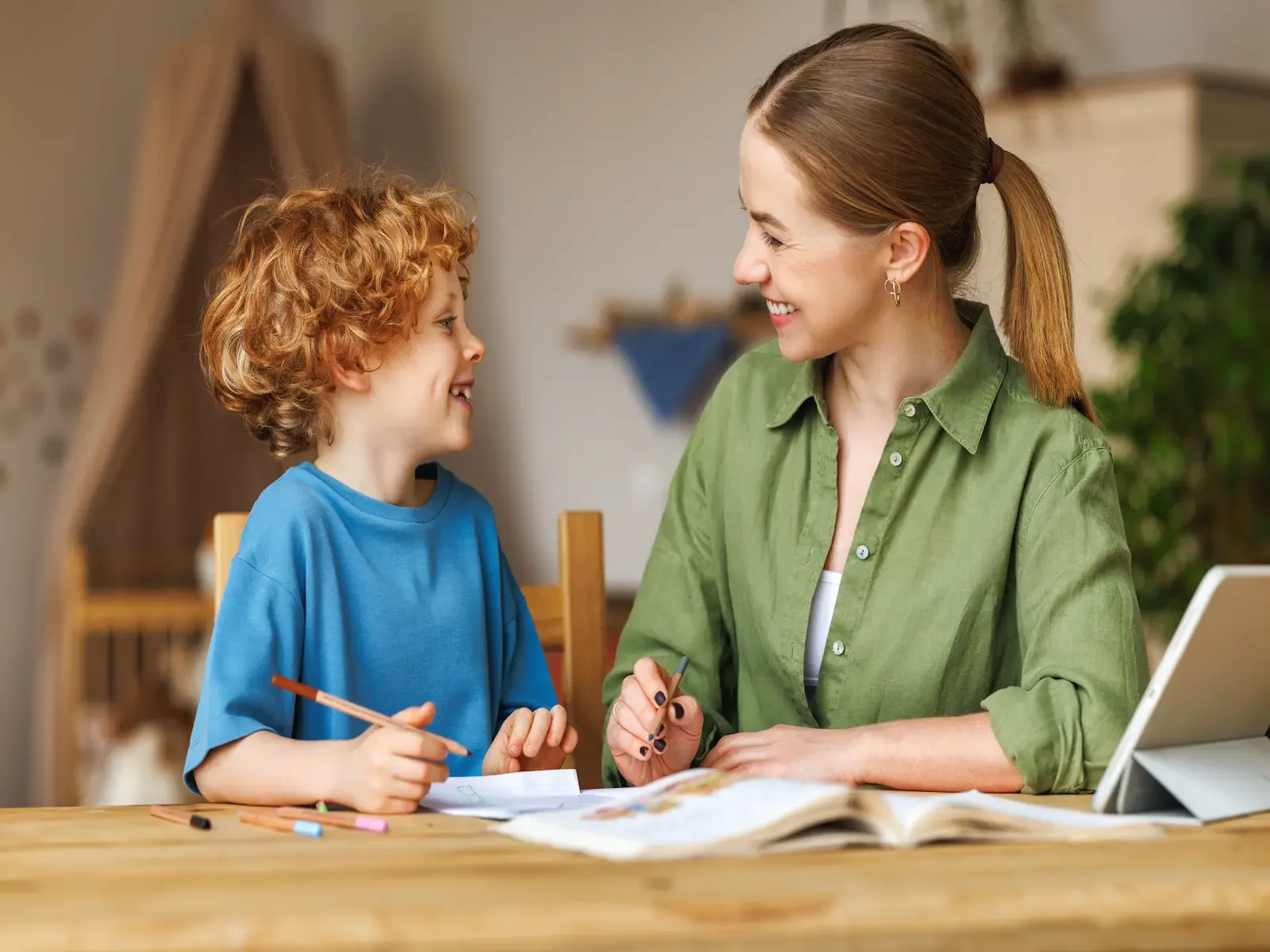 Tutor smiling and helping a young student during a one-on-one tutoring session, showing positive connection and encouragement at APRISE Learning.