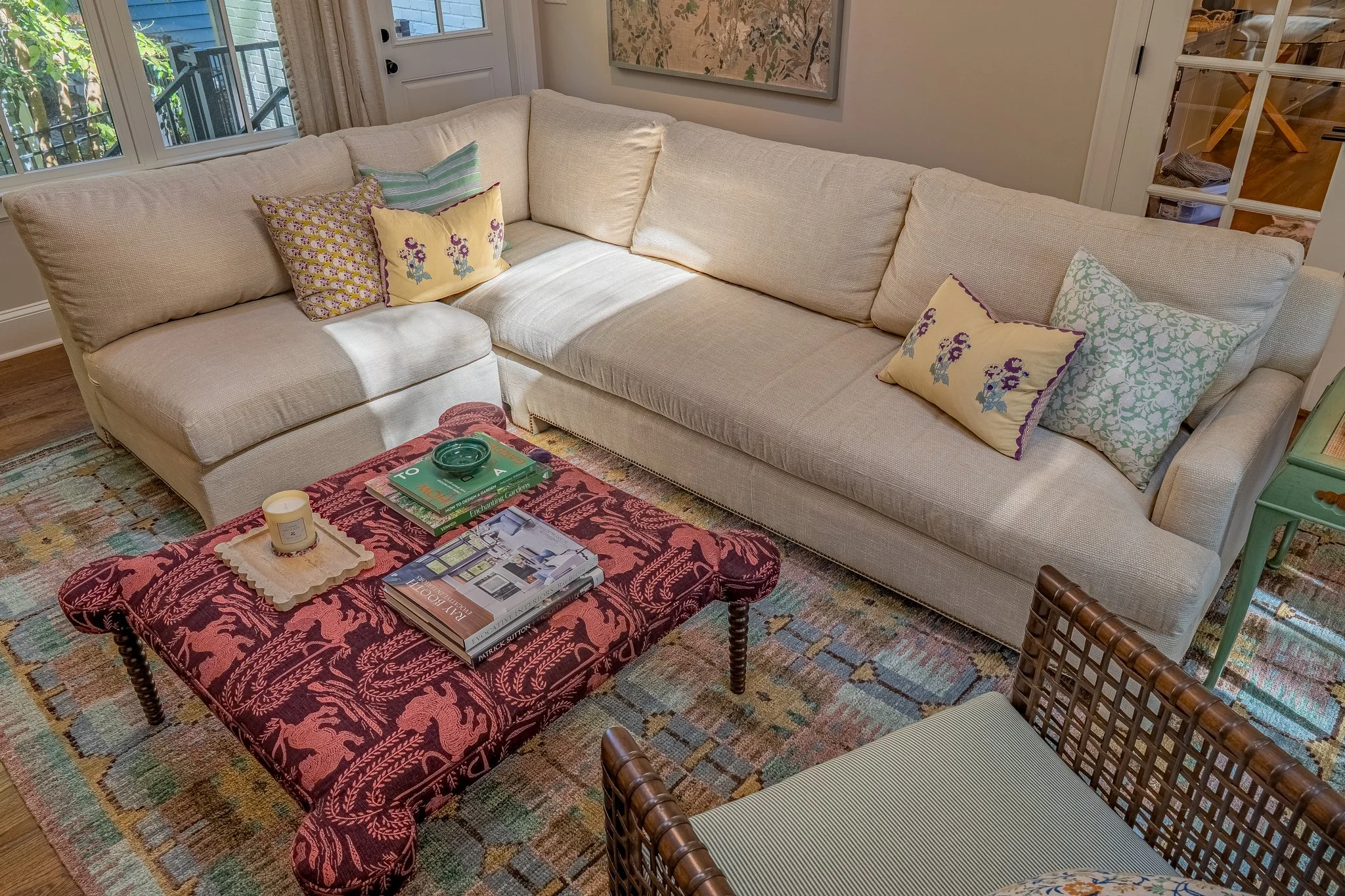 custom neutral sectional with floral cushions and plum dramatic ottoman