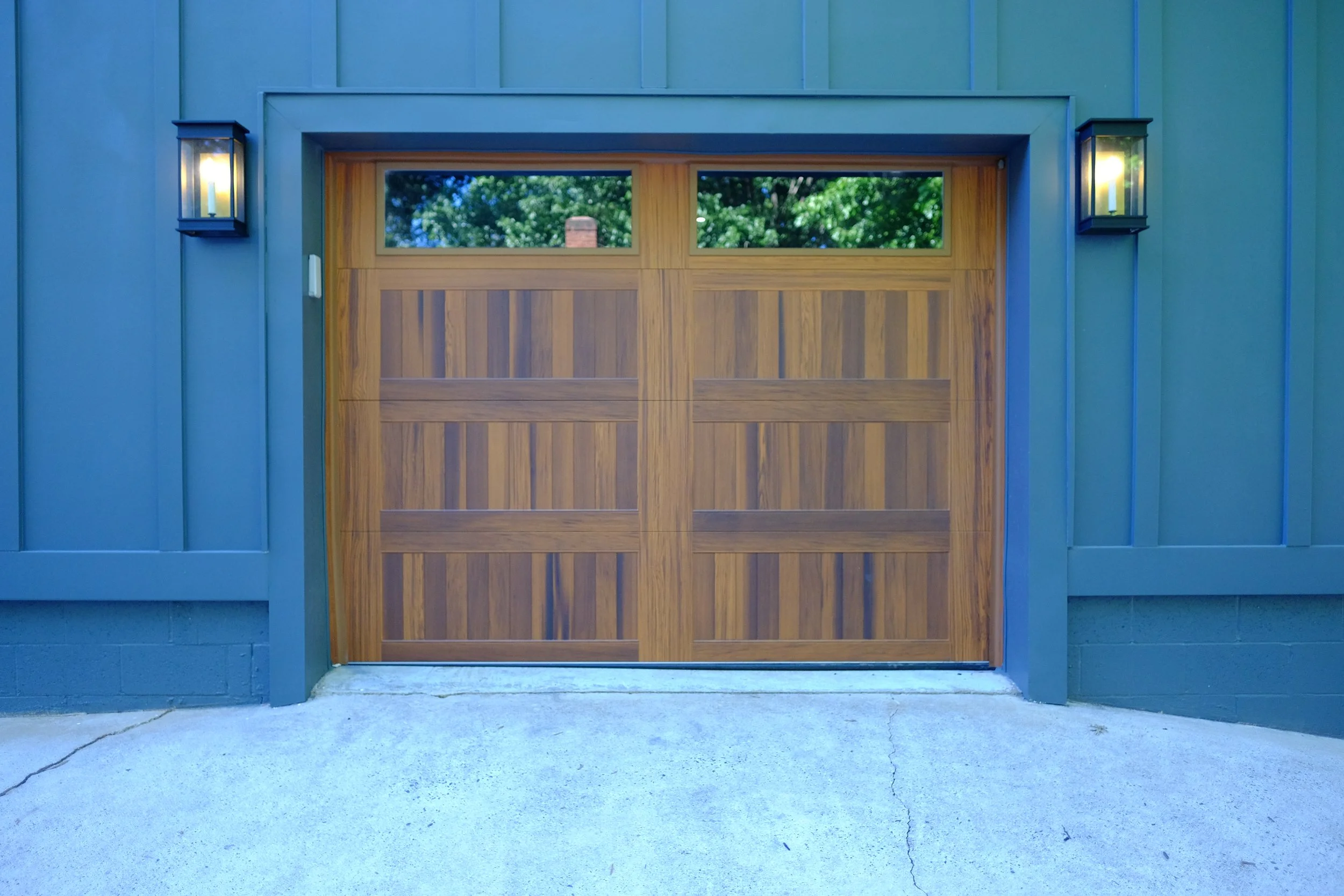 top lit wooden garage door with exterior lanterns