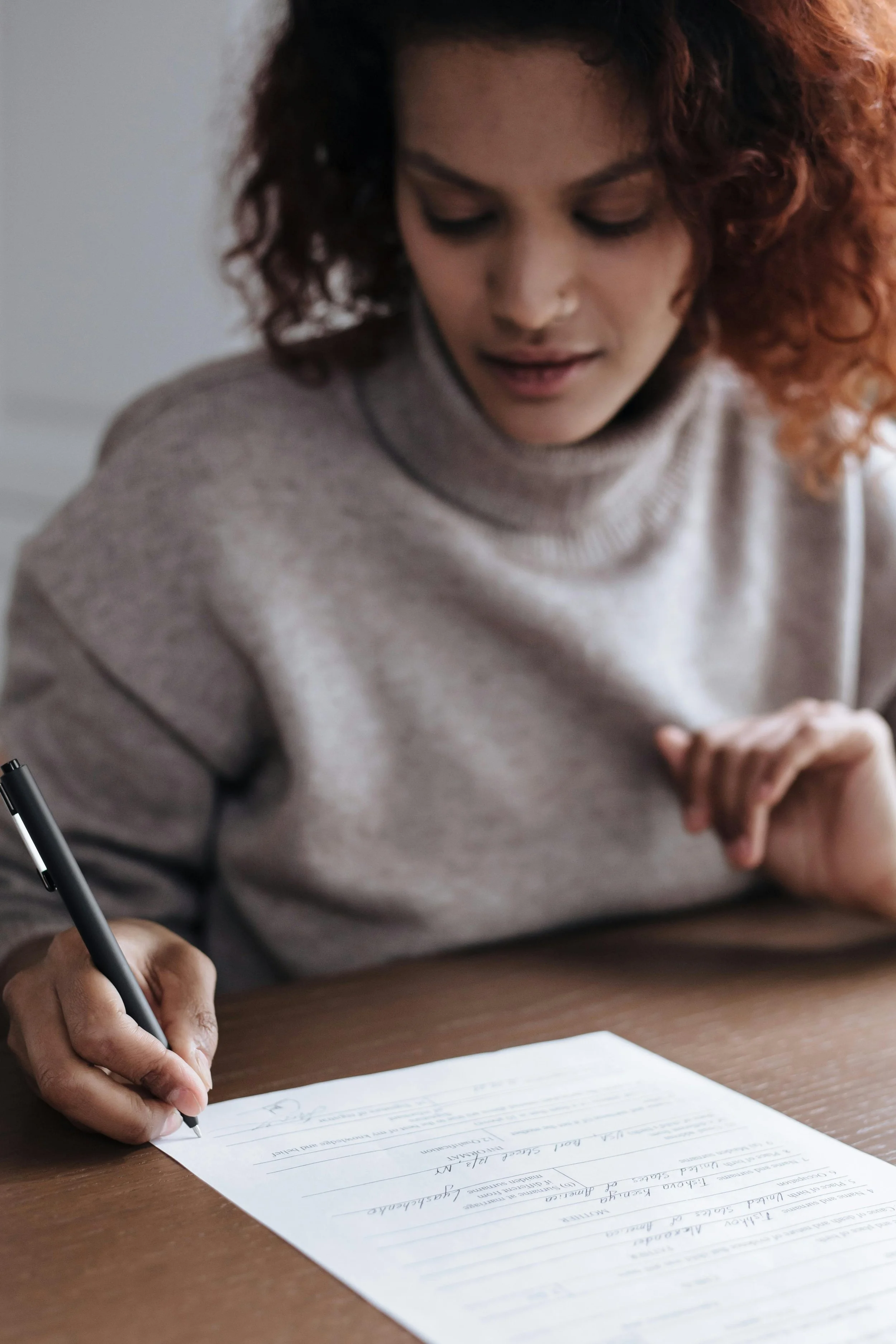 A woman signing a legal document with a black pen.