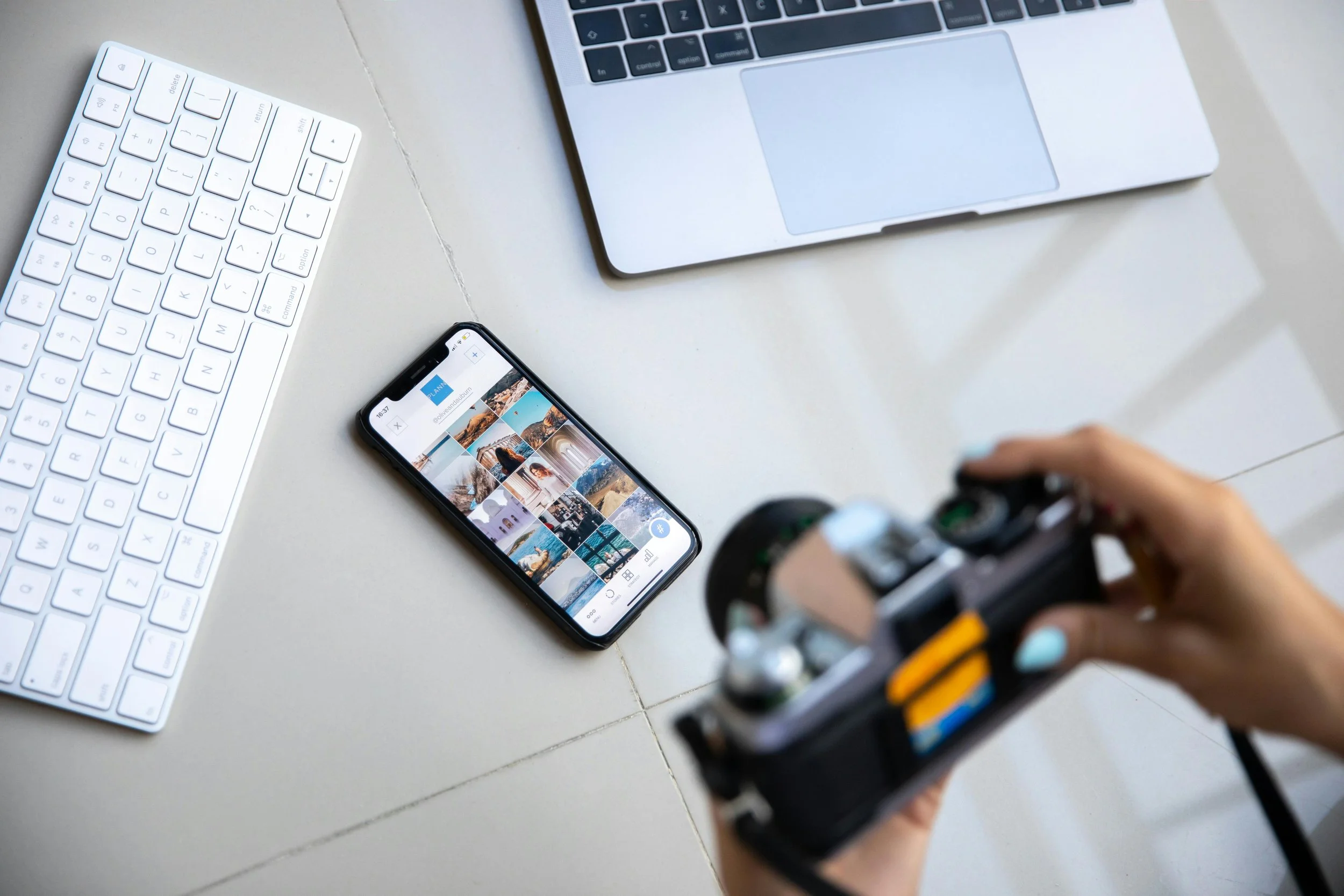 Creative professional reviewing content on phone with camera and laptop, marketing workspace flatlay