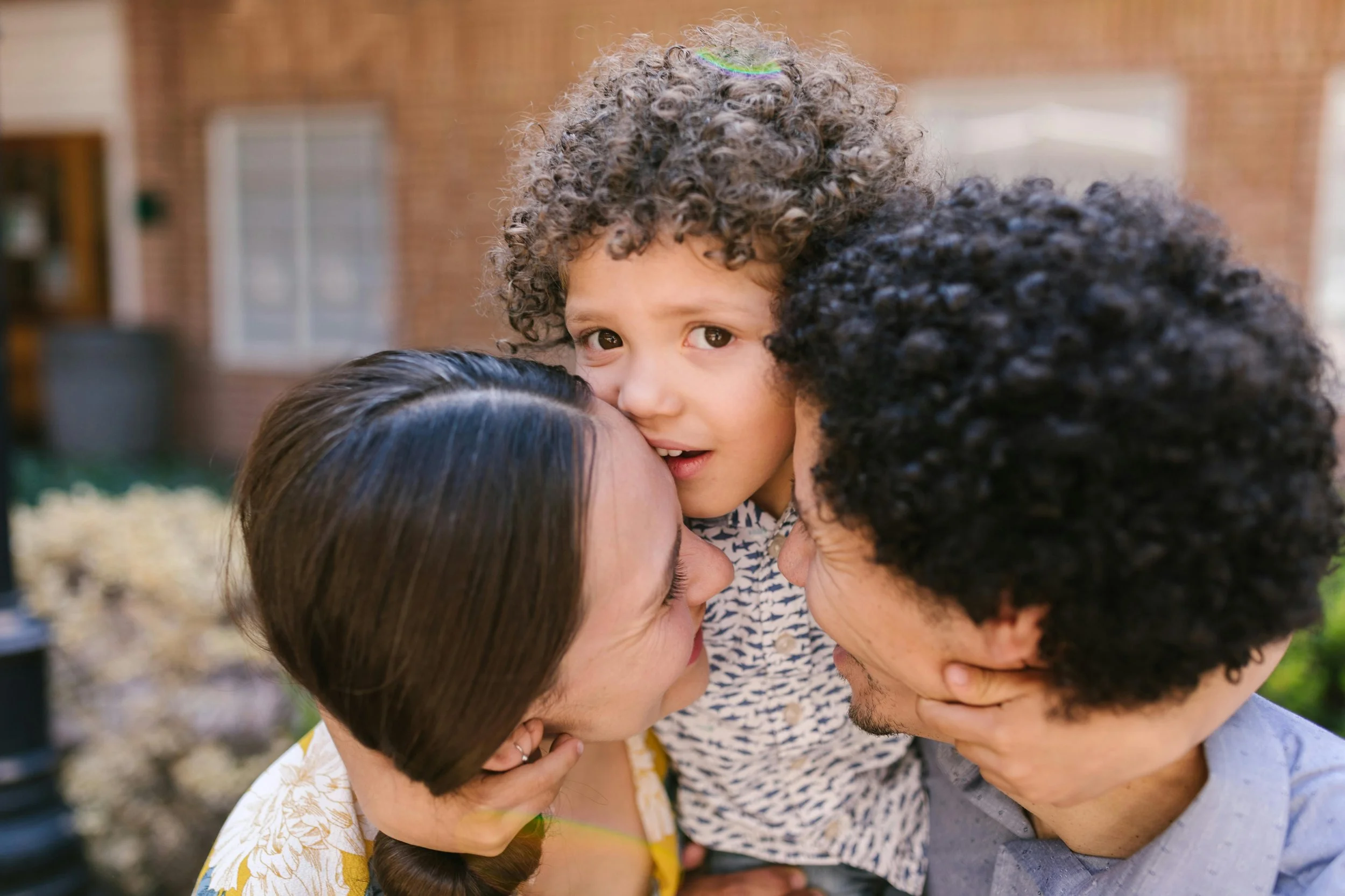 A mother, father and child in a warm embrace, sharing a tender moment.