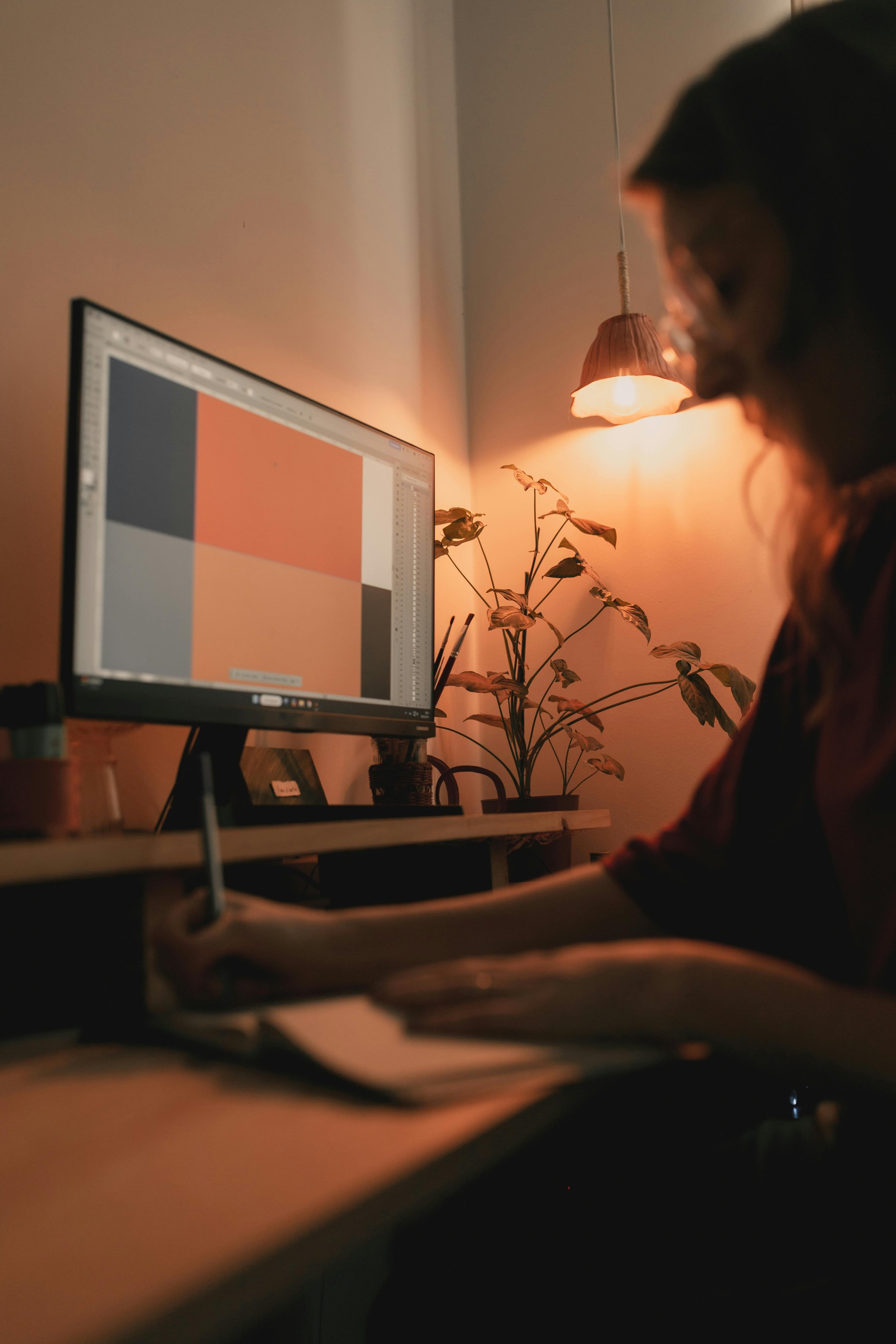 Creative professional working at screen in warmly lit studio