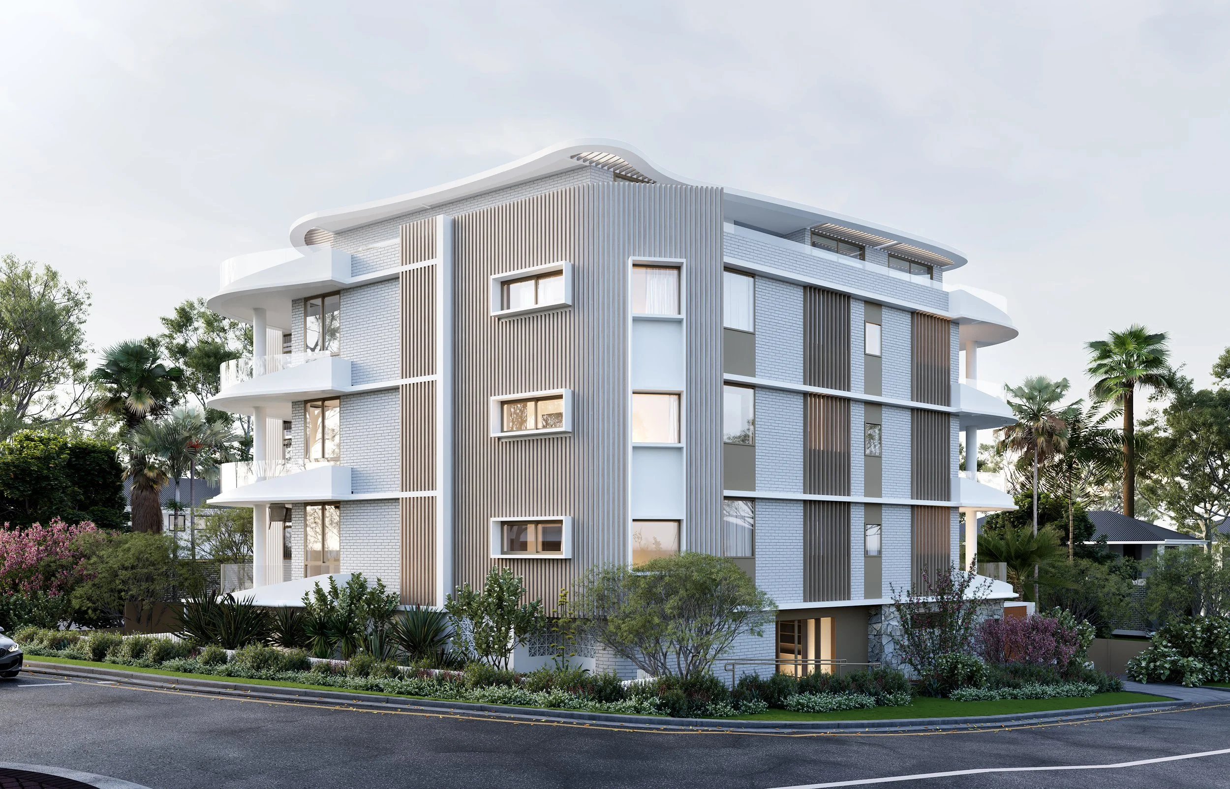 Modern apartment building with white and gray facade, surrounded by greenery and palm trees, situated on a corner street.