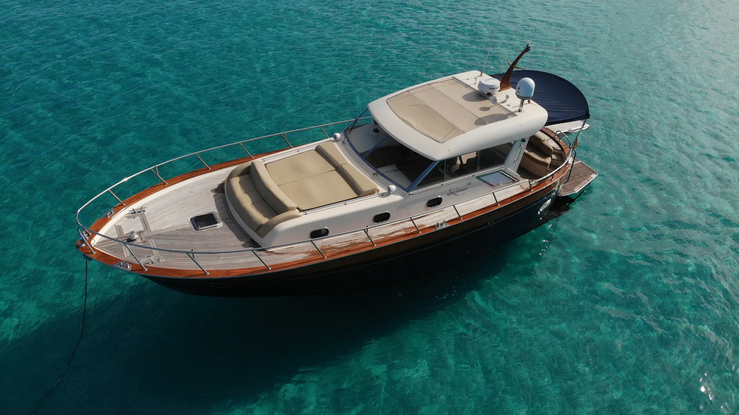 apreamare 45 scamp gliding along the coastline showing its wide deck and elegant wooden details.