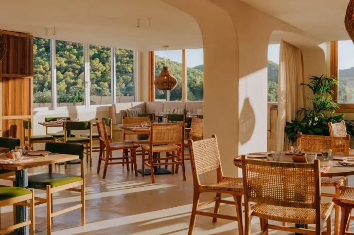 modern restaurant interior with wooden furniture and large windows overlooking greenery